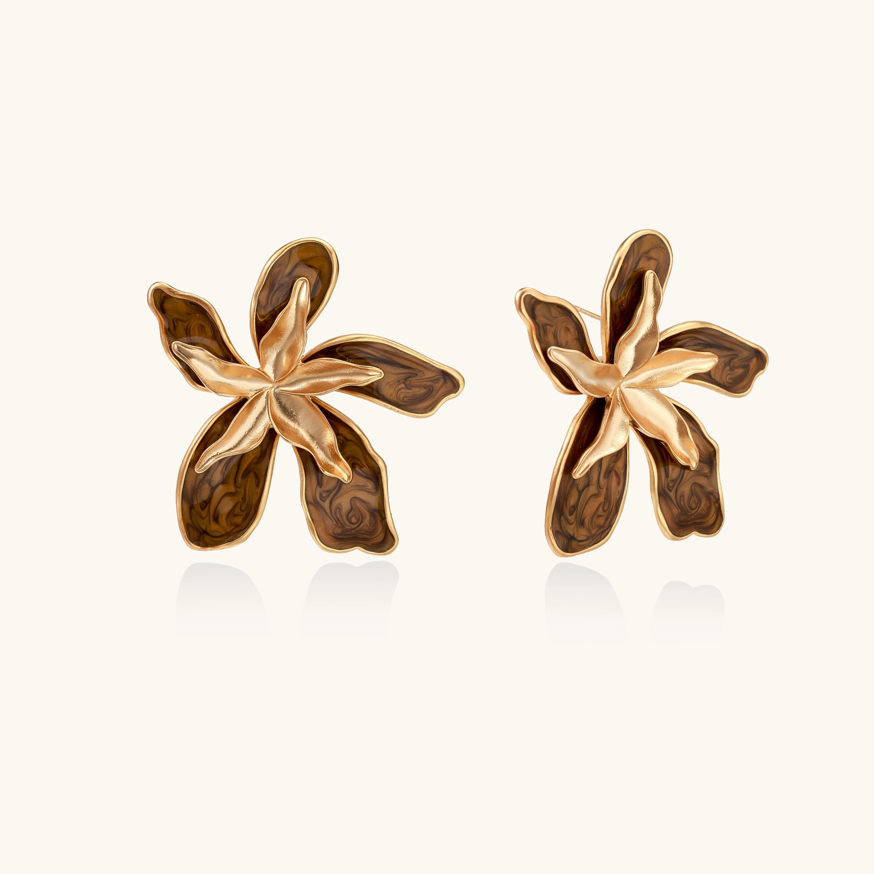 Gold-plated brass flower earrings with brown tortoiseshell enamel petals on cream background