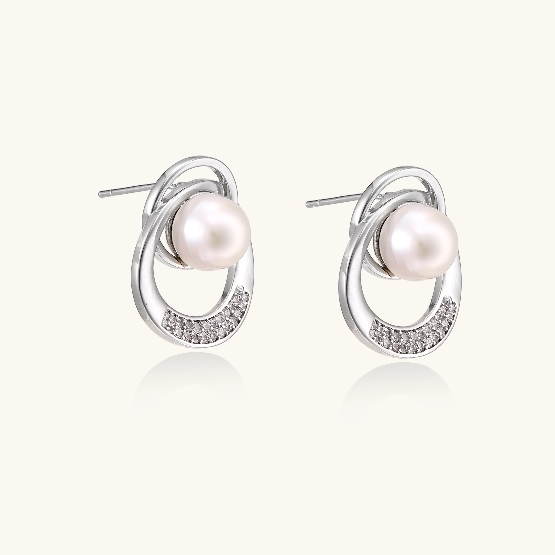 White gold-plated brass earrings with circular design, freshwater pearl center, and diamond accents