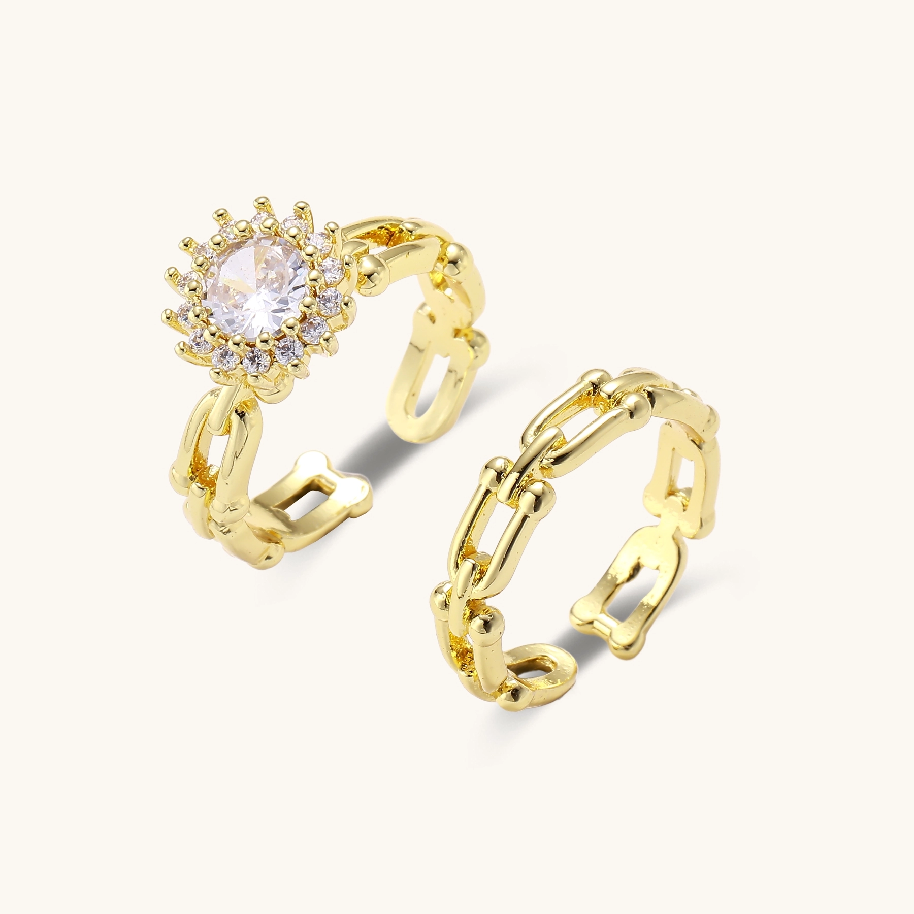 Two adjustable gold rings: chain-link band and halo-style ring with cubic zirconia stones on cream background