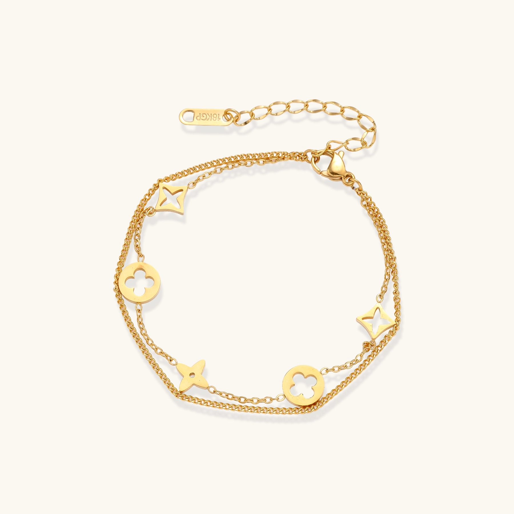 Double-layer gold-plated bracelet with quatrefoil and star charms on cream background, 18K gold finish.
