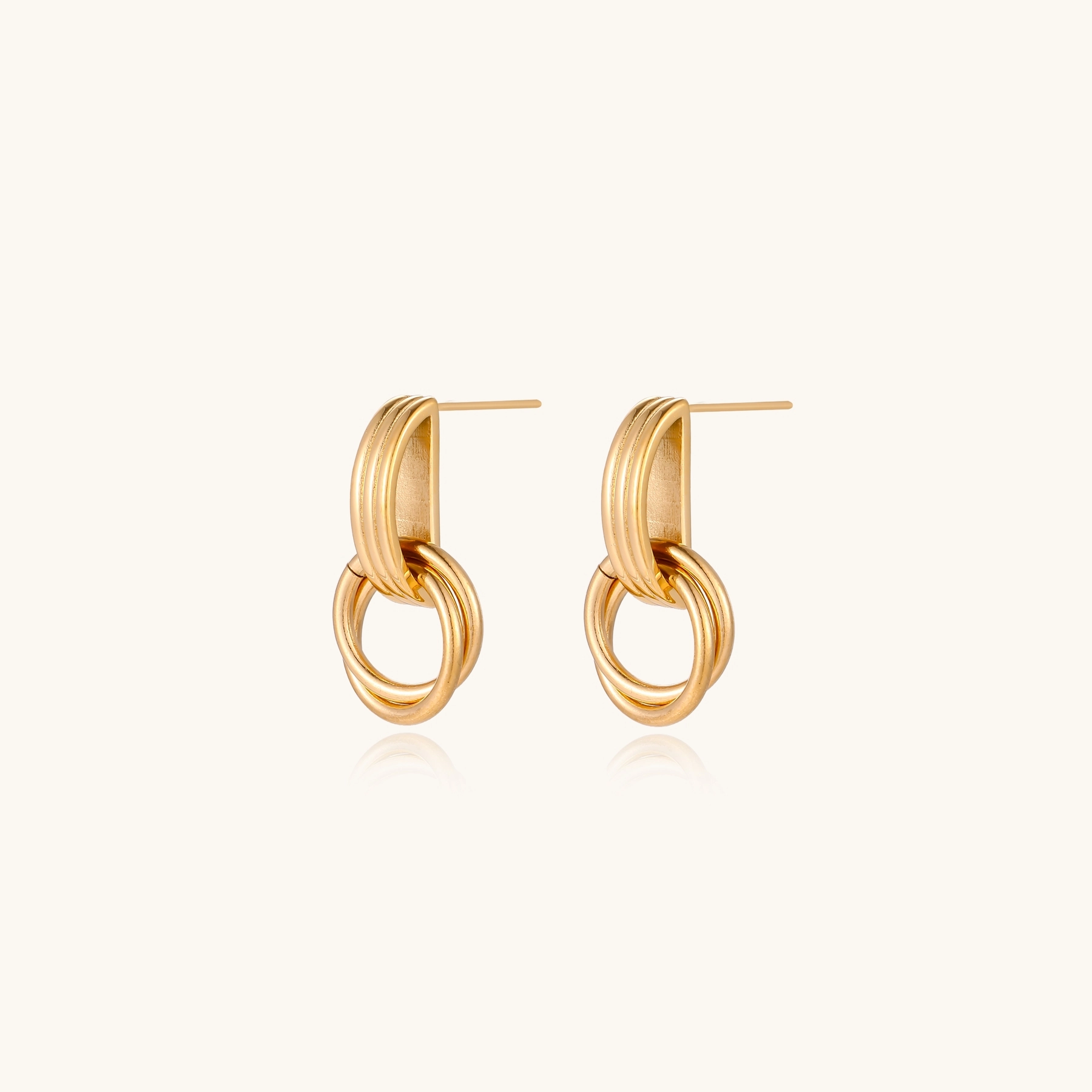Gold stud earrings with vertical ridged bar connecting to triple interlocking circular rings on white background