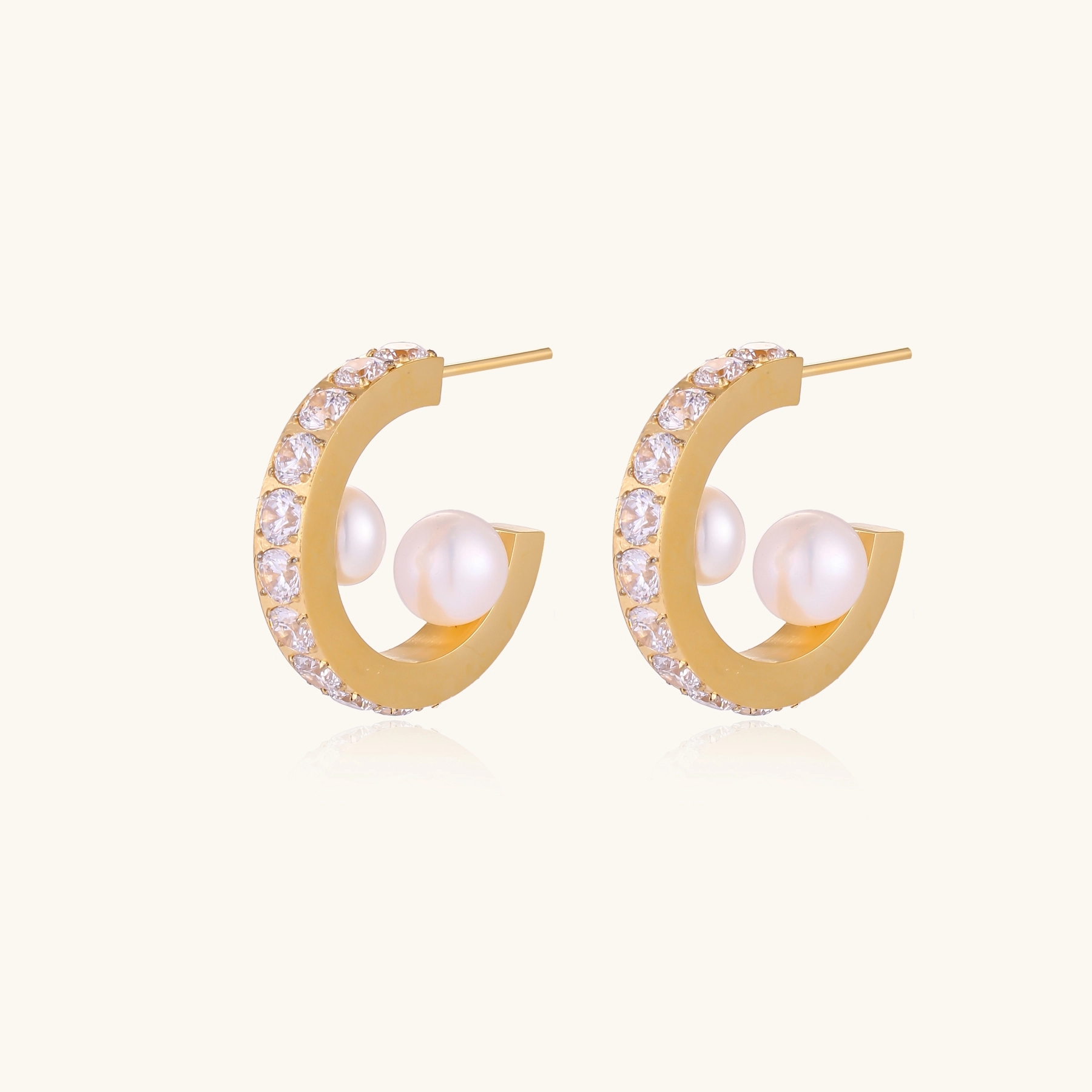 Gold pavé hoop earrings with two freshwater pearls nestled inside the curved design, featuring crystal-studded outer edge.