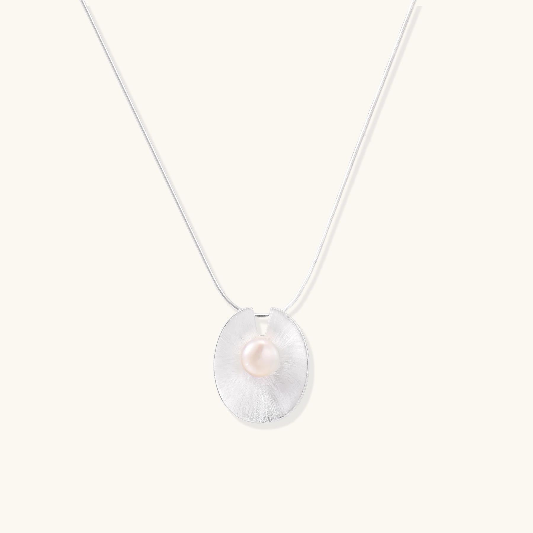 Sterling silver disc necklace with textured finish and centered freshwater pearl on delicate chain