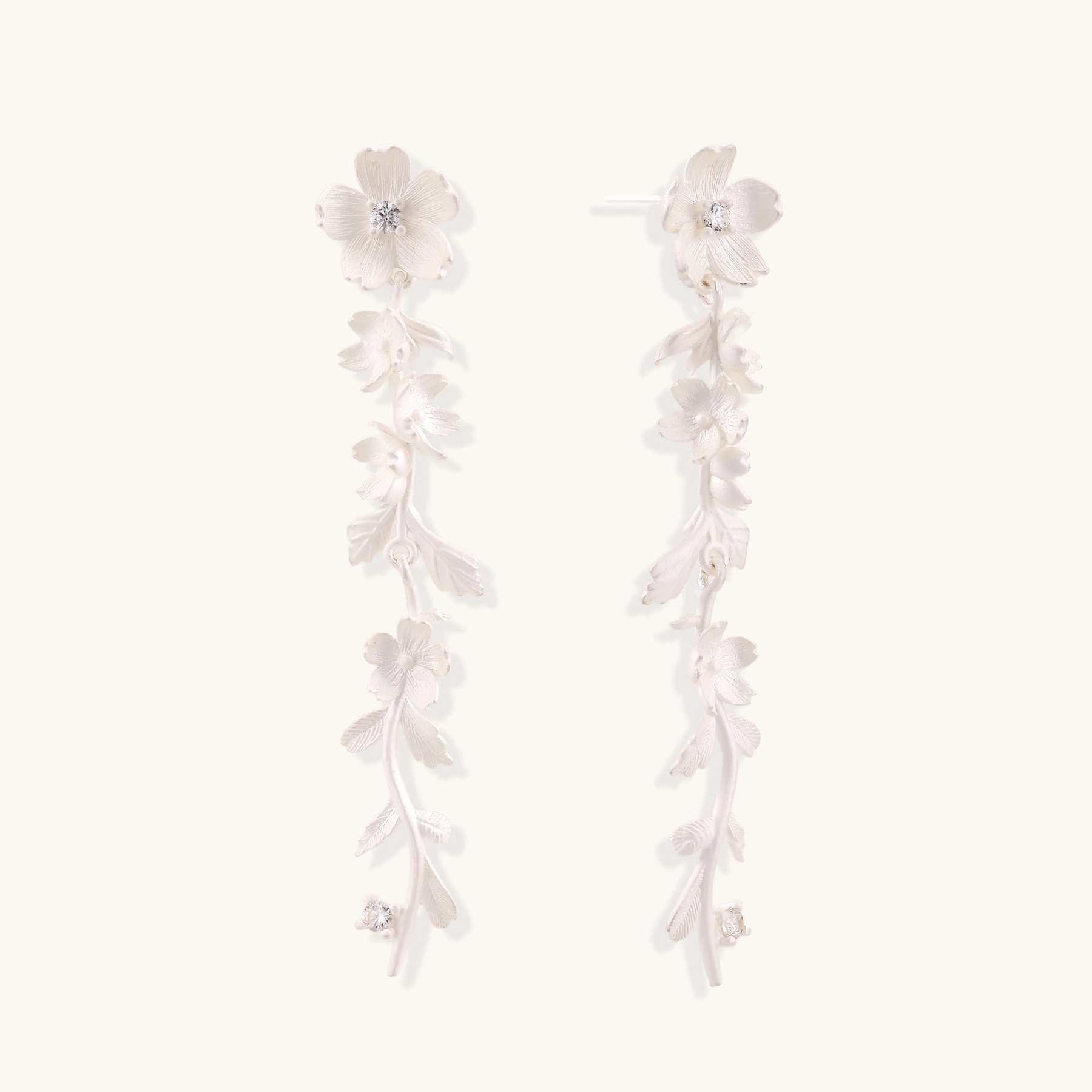 Long sterling silver drop earrings with delicate floral vine design and crystal accents on white background