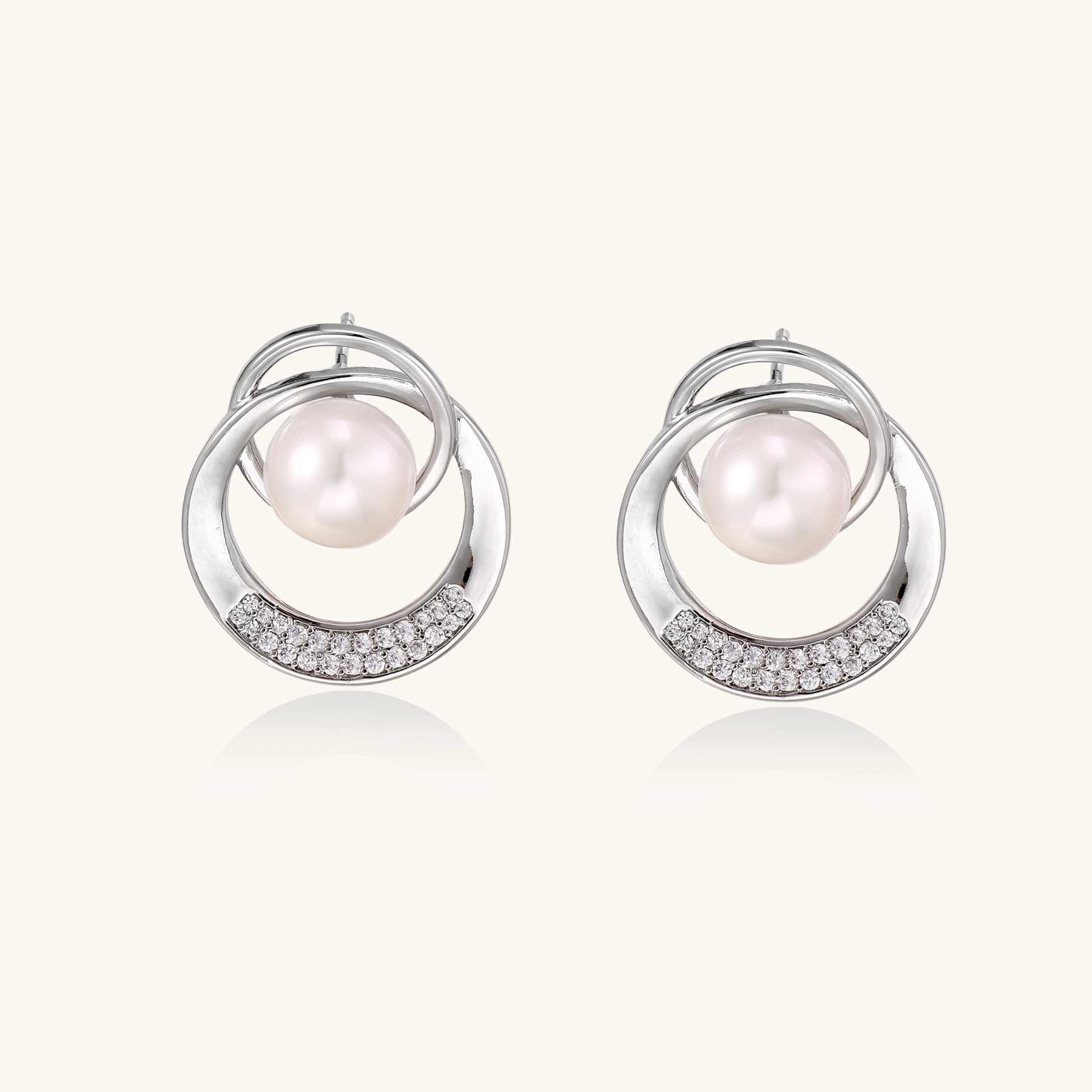 White gold-plated brass earrings with circular design, freshwater pearl center, and diamond accents