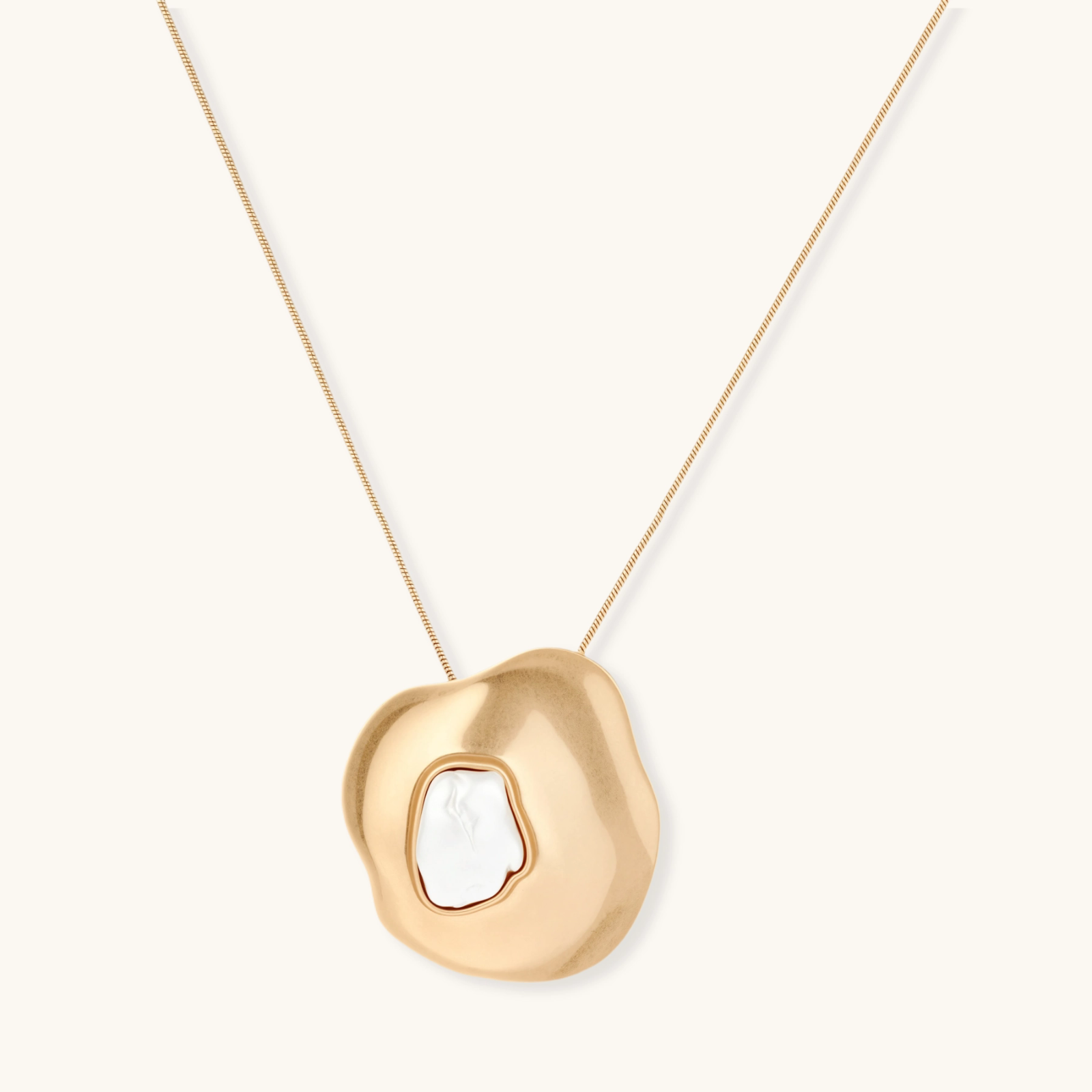 Organic-shaped gold pendant necklace with baroque pearl accent on adjustable chain, displayed against neutral background.
