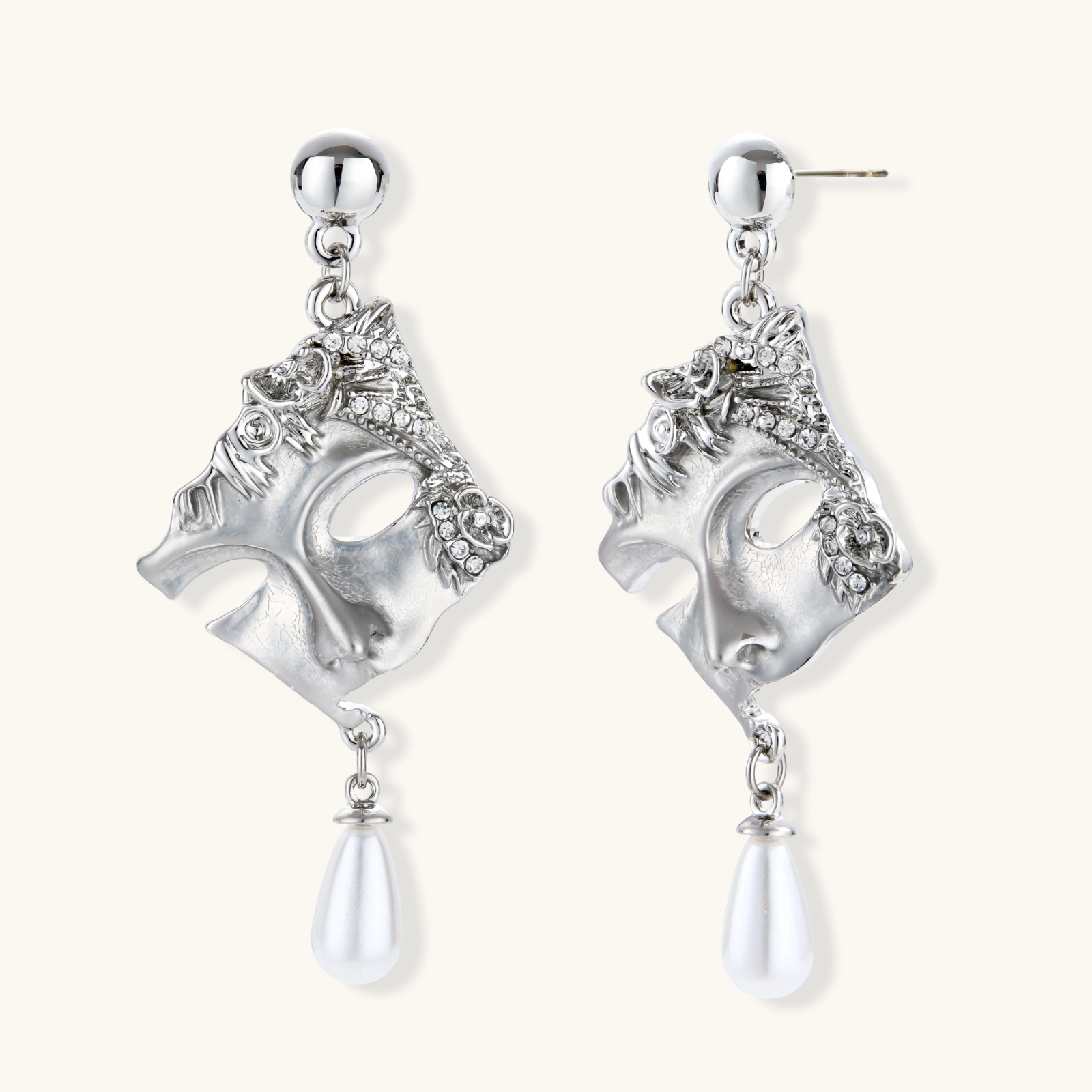 Ornate silver-toned theatrical mask earrings with crystal details and pearl drops on white background.