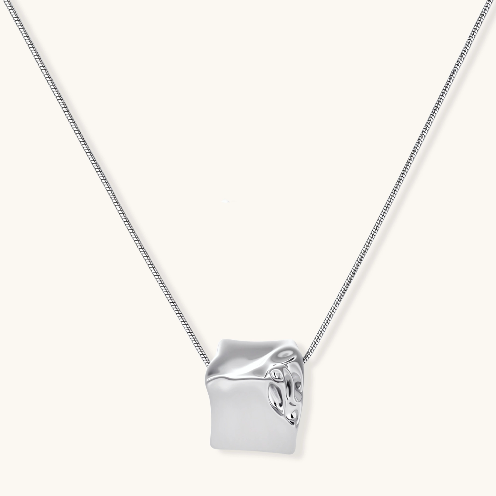 Modern cube pendant with liquid metal draping detail on adjustable chain, available in gold and silver finishes