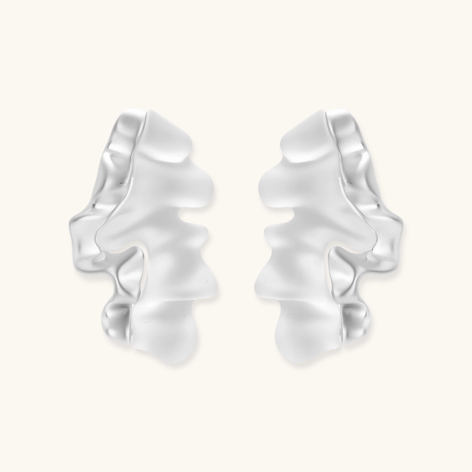 Sculptural wave-textured statement earrings with flowing organic ridges in metallic finish on cream background