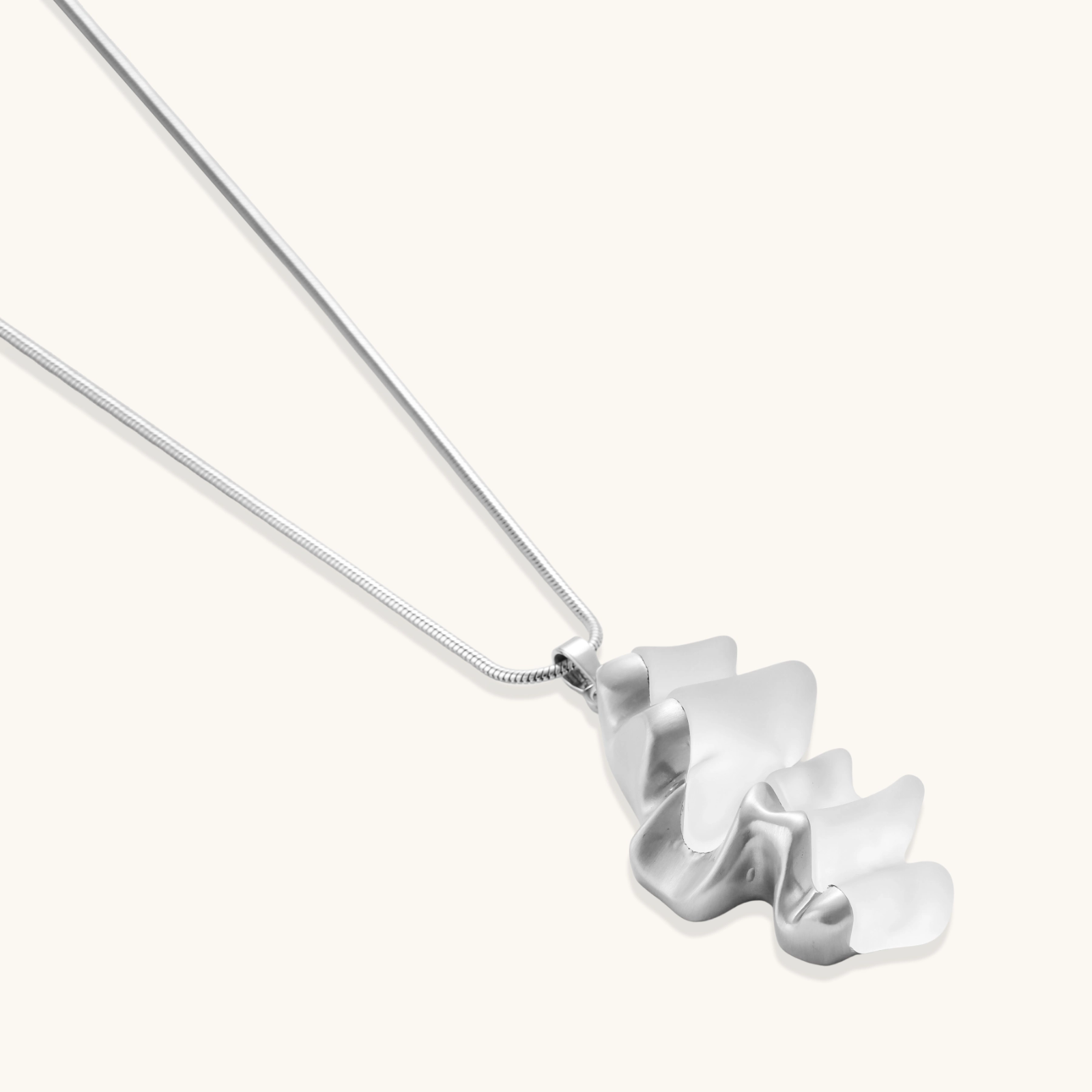 Close-up of a sculptural necklace with flowing wave pendant made from eco-zinc alloy on adjustable chain