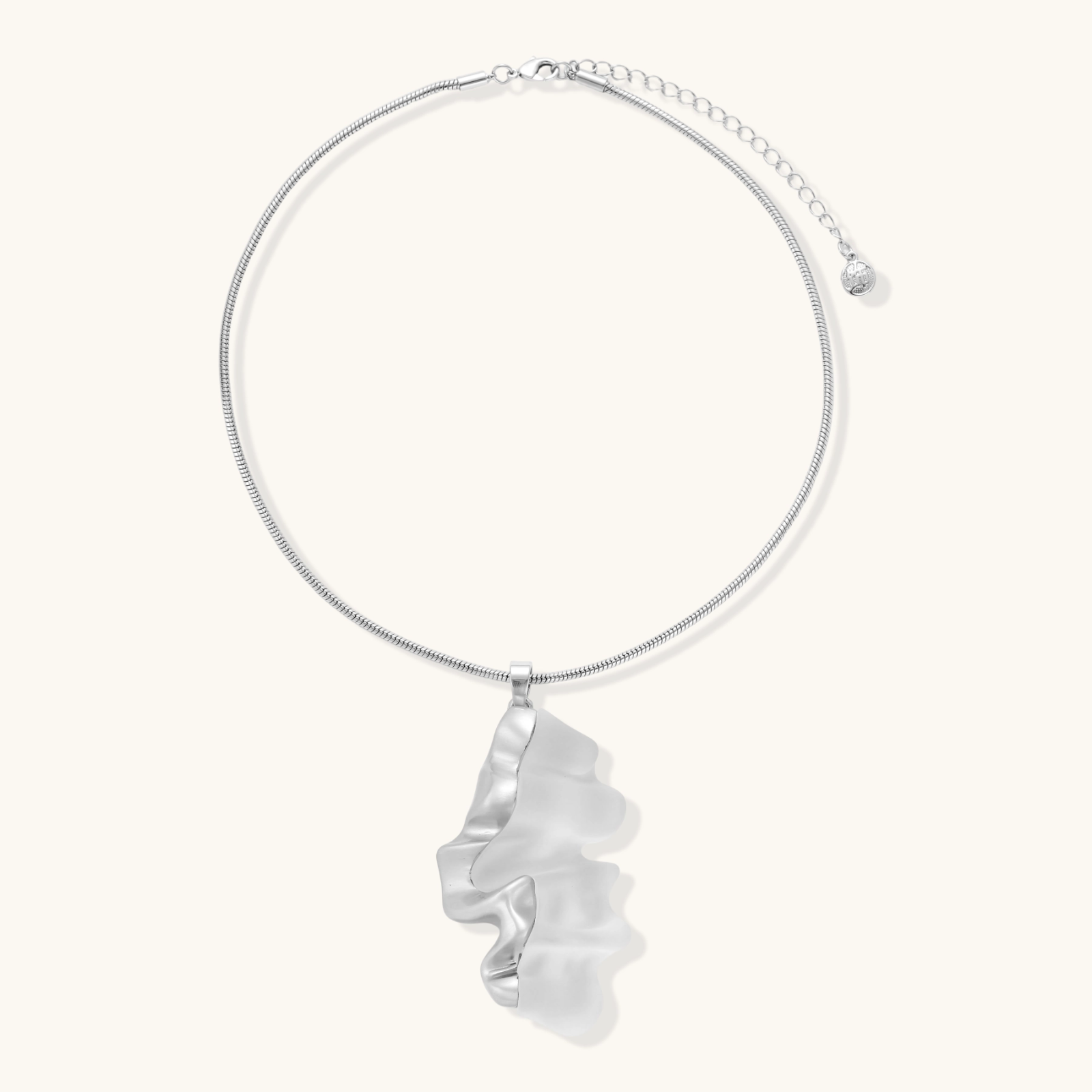 Close-up of a sculptural necklace with flowing wave pendant made from eco-zinc alloy on adjustable chain