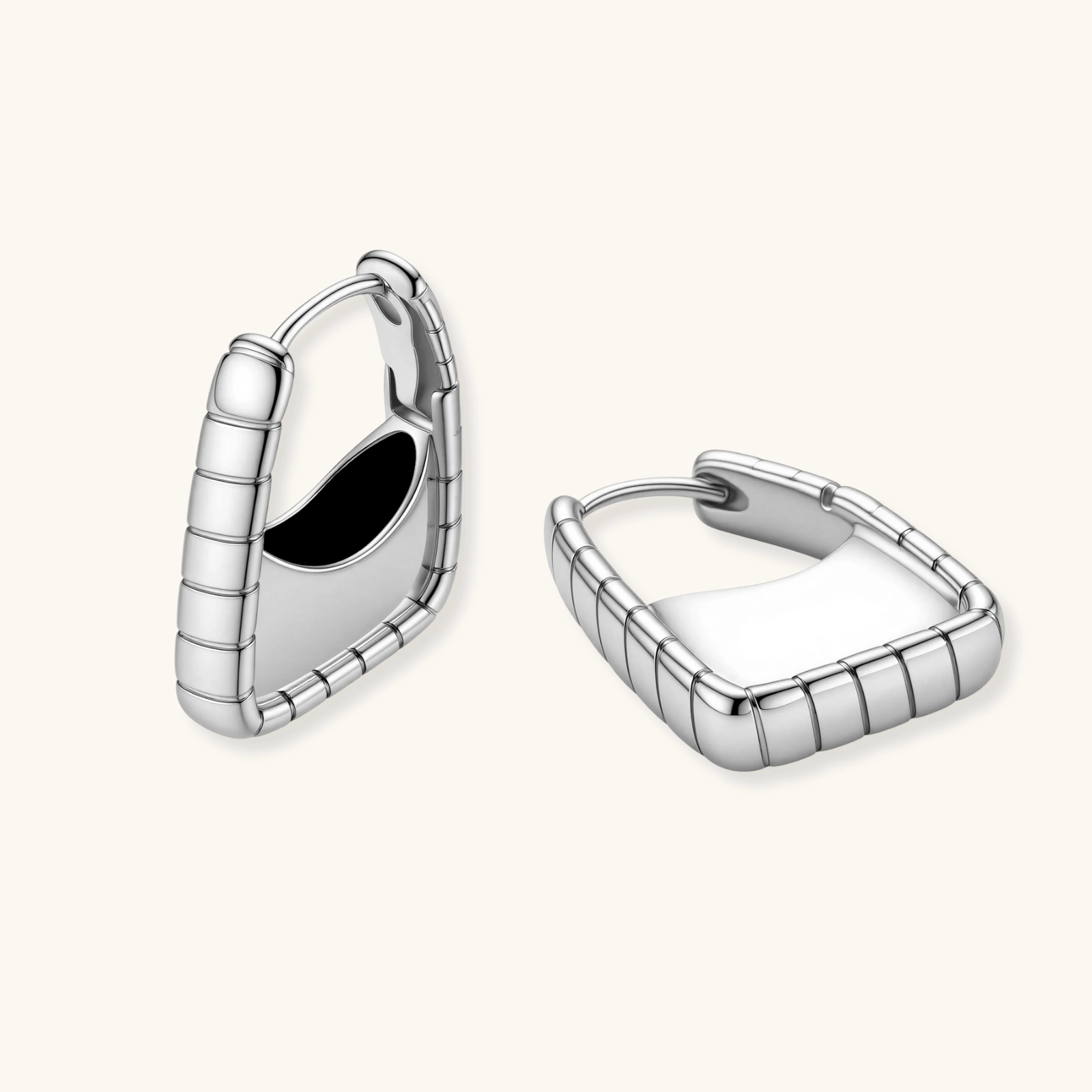 Close-up of platinum-plated sterling silver hoop earrings with horizontal textured grooves on white background.