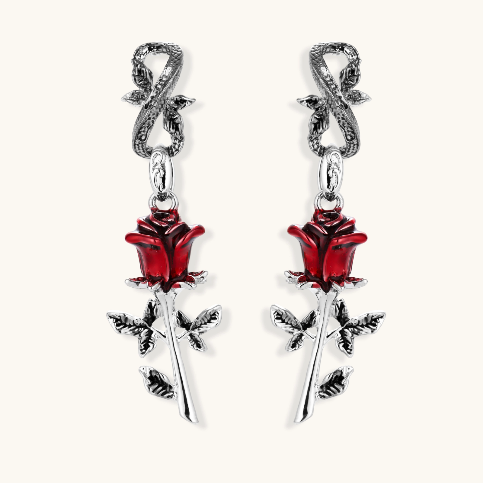 Gothic dangle earrings featuring silver serpent hooks with red enamel roses and metallic stems on white background.