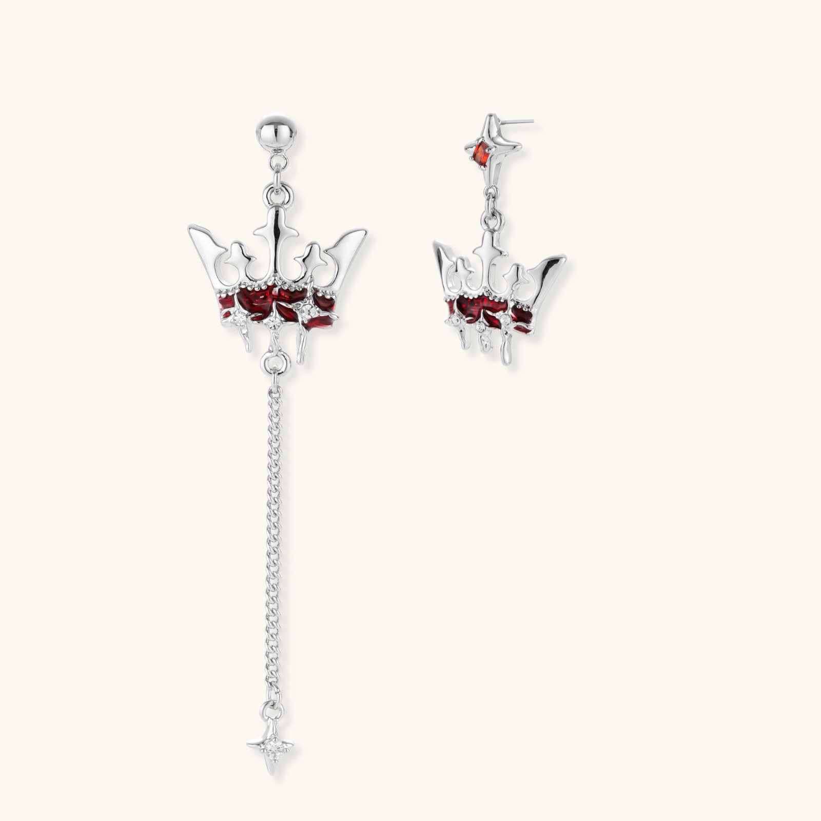 Asymmetrical crown-shaped stud earrings with red zirconia stones, one featuring a silver chain with star charm