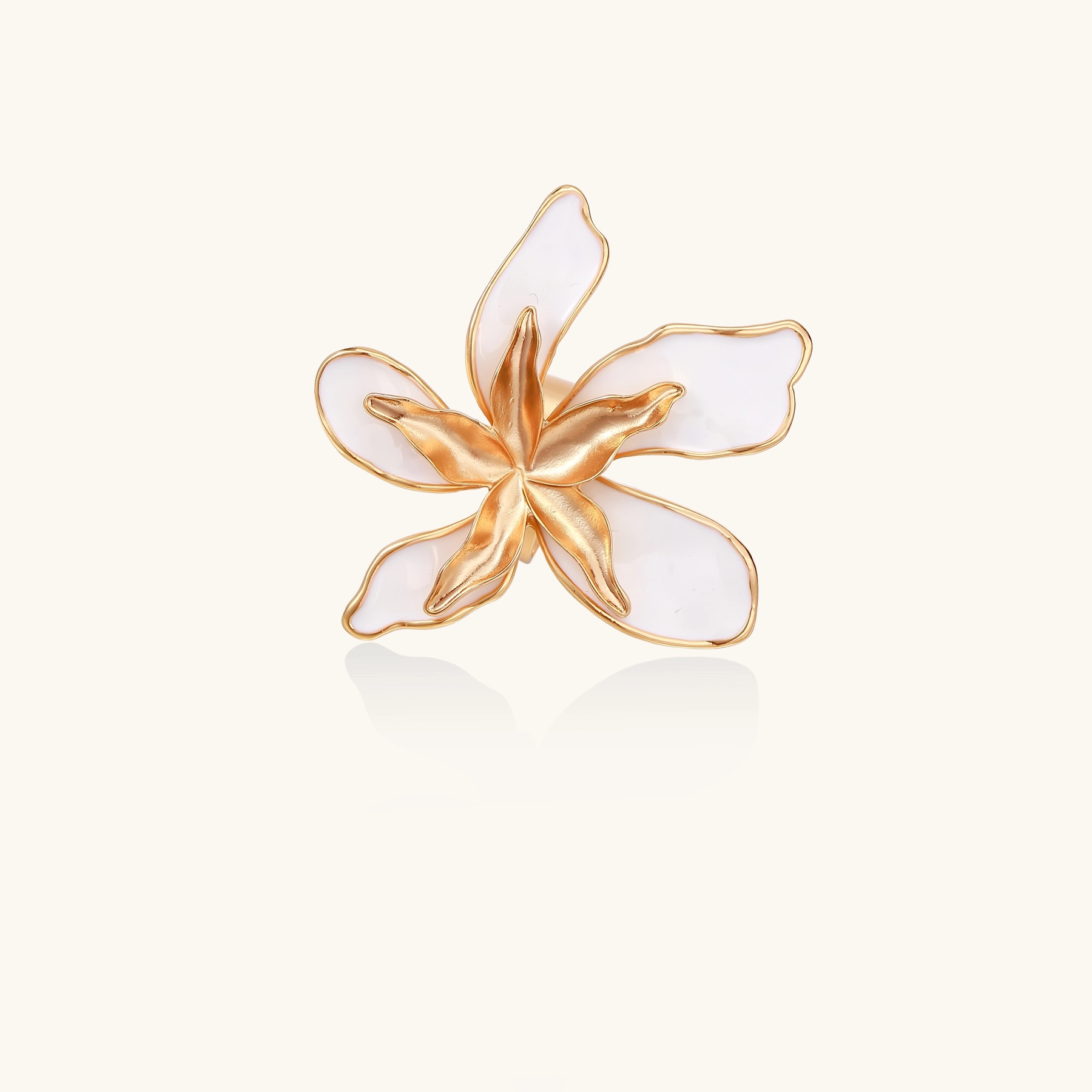 Gold-plated sculptural ring featuring white enamel petals forming an oversized lily bloom on adjustable band