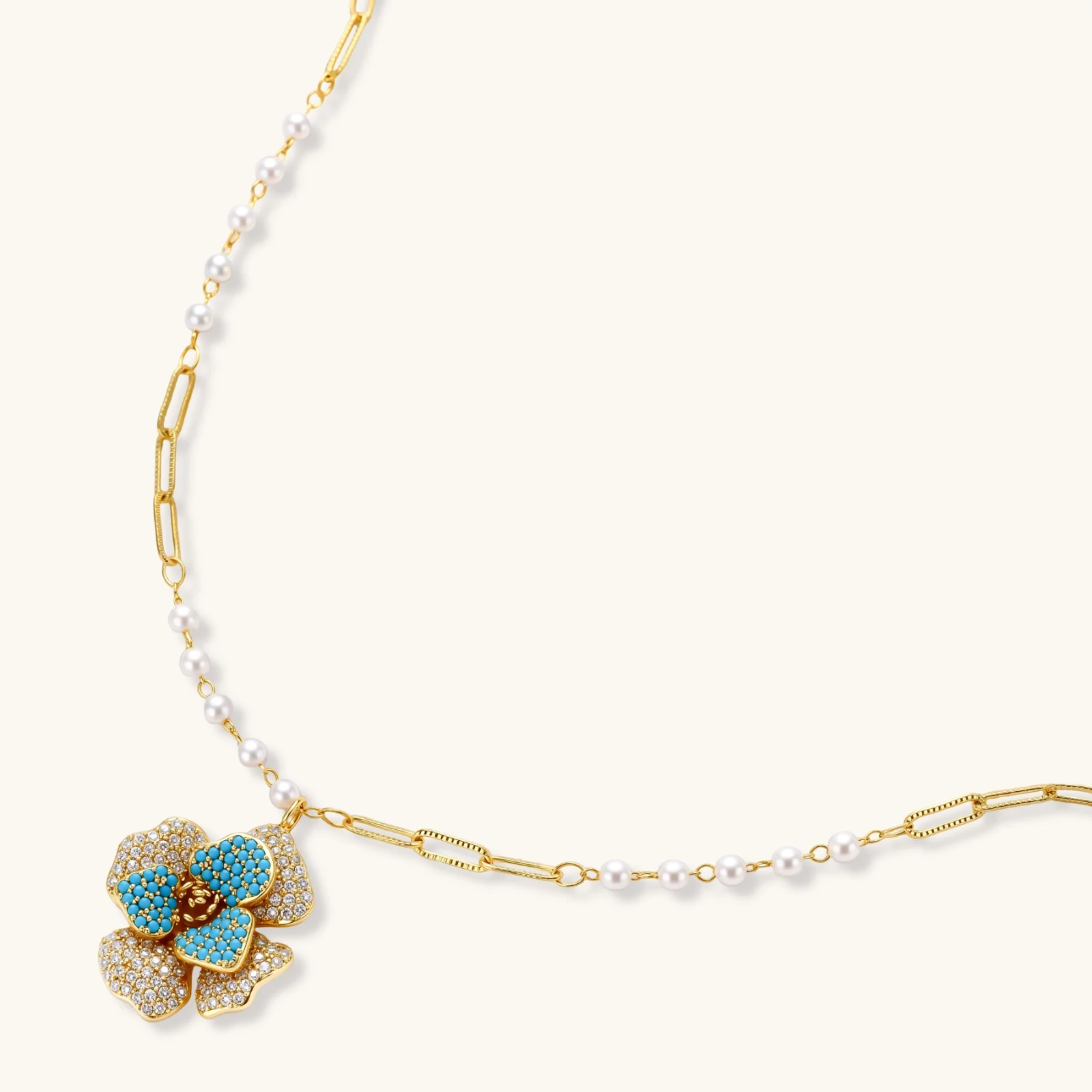 14K gold-plated floral jewelry set with blue cubic zirconia centers and pearl chain details on white background.