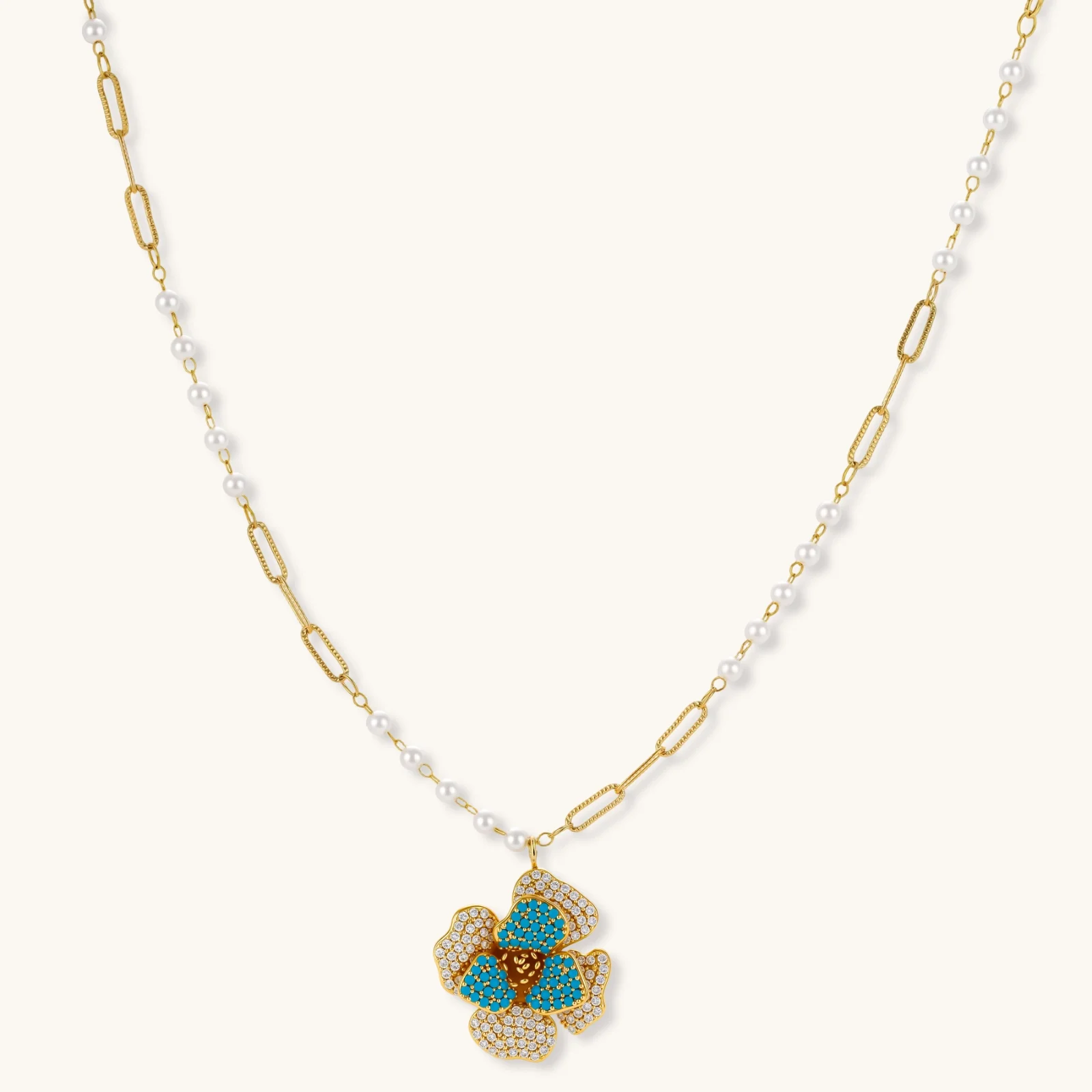 14K gold-plated floral jewelry set with blue cubic zirconia centers and pearl chain details on white background.