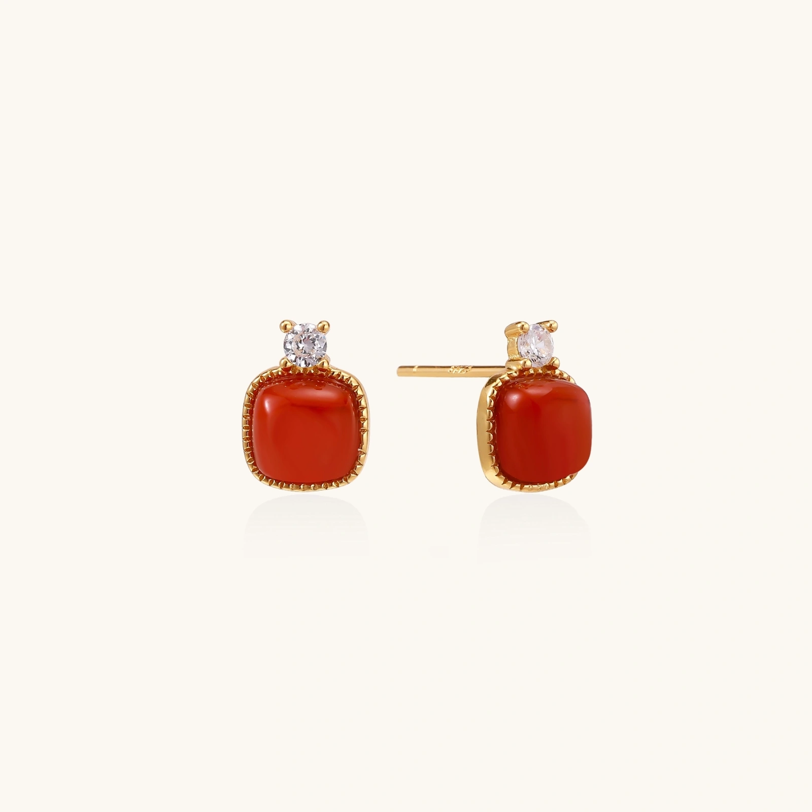 18K gold vermeil stud earrings with cushion-cut red agate stones and sparkling crystal accents on beige background