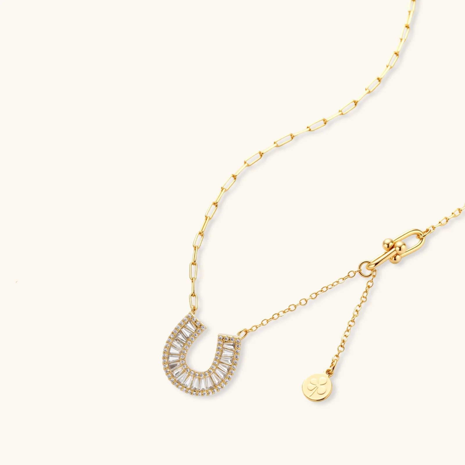 Sparkling horseshoe-shaped jewelry set with AAA cubic zirconia in gold-plated and white gold finishes on cream background.