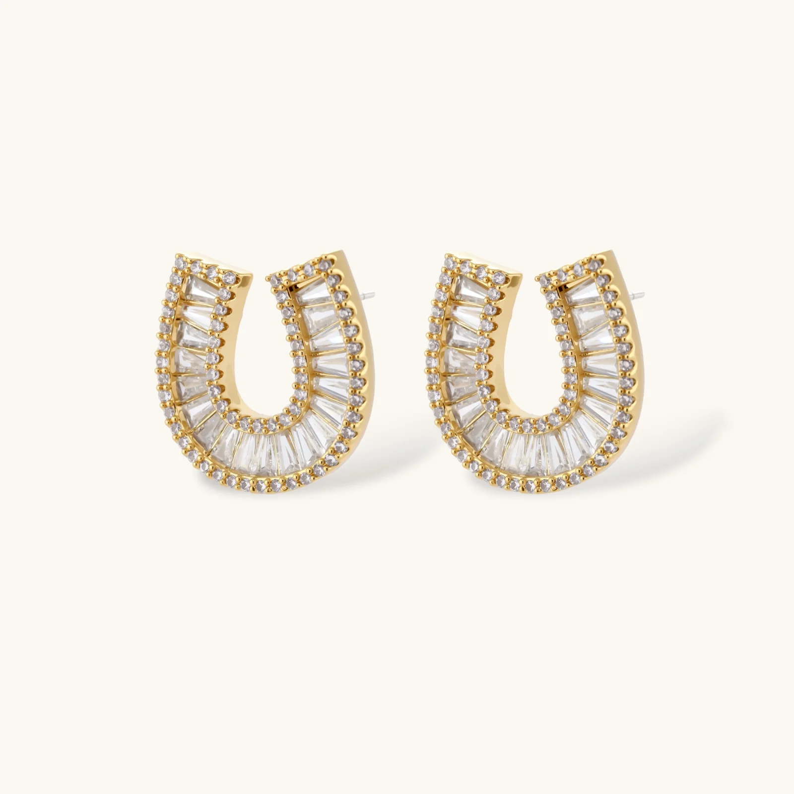Sparkling horseshoe-shaped jewelry set with AAA cubic zirconia in gold-plated and white gold finishes on cream background.