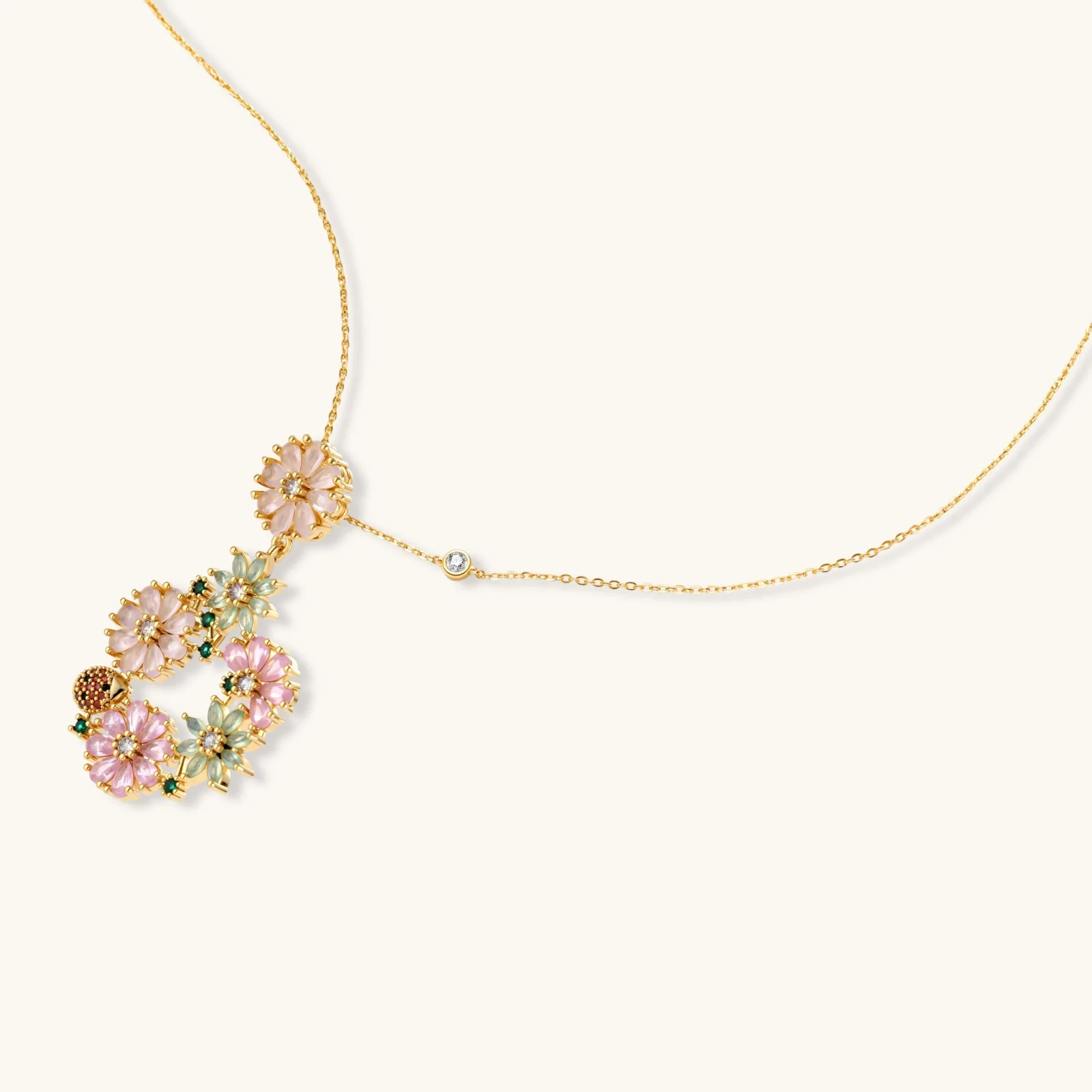 14K gold plated jewelry set with pink and green cubic zirconia flowers arranged in wreath design on cream background