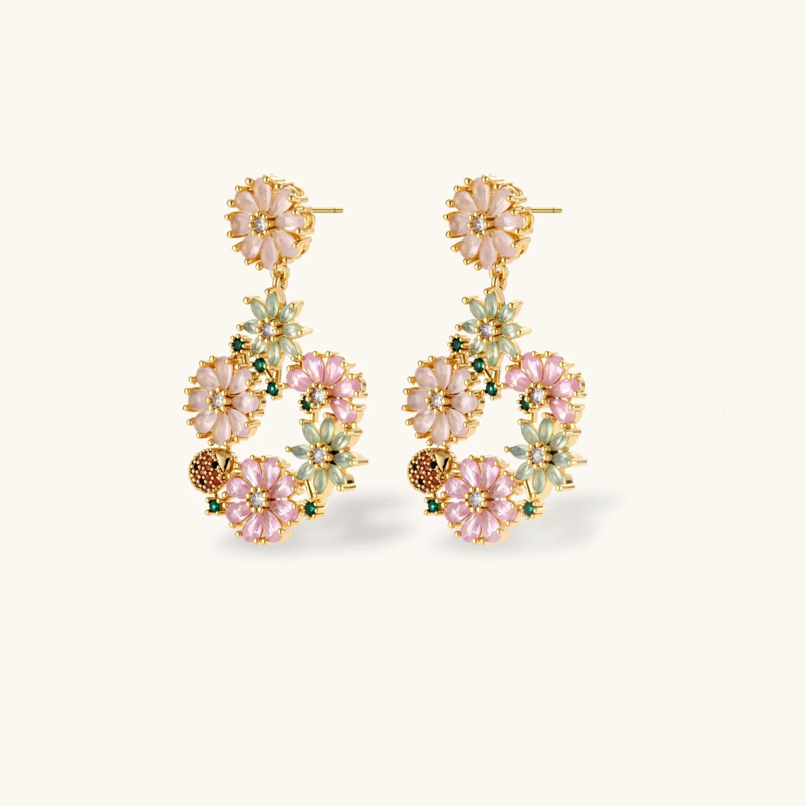 14K gold plated jewelry set with pink and green cubic zirconia flowers arranged in wreath design on cream background