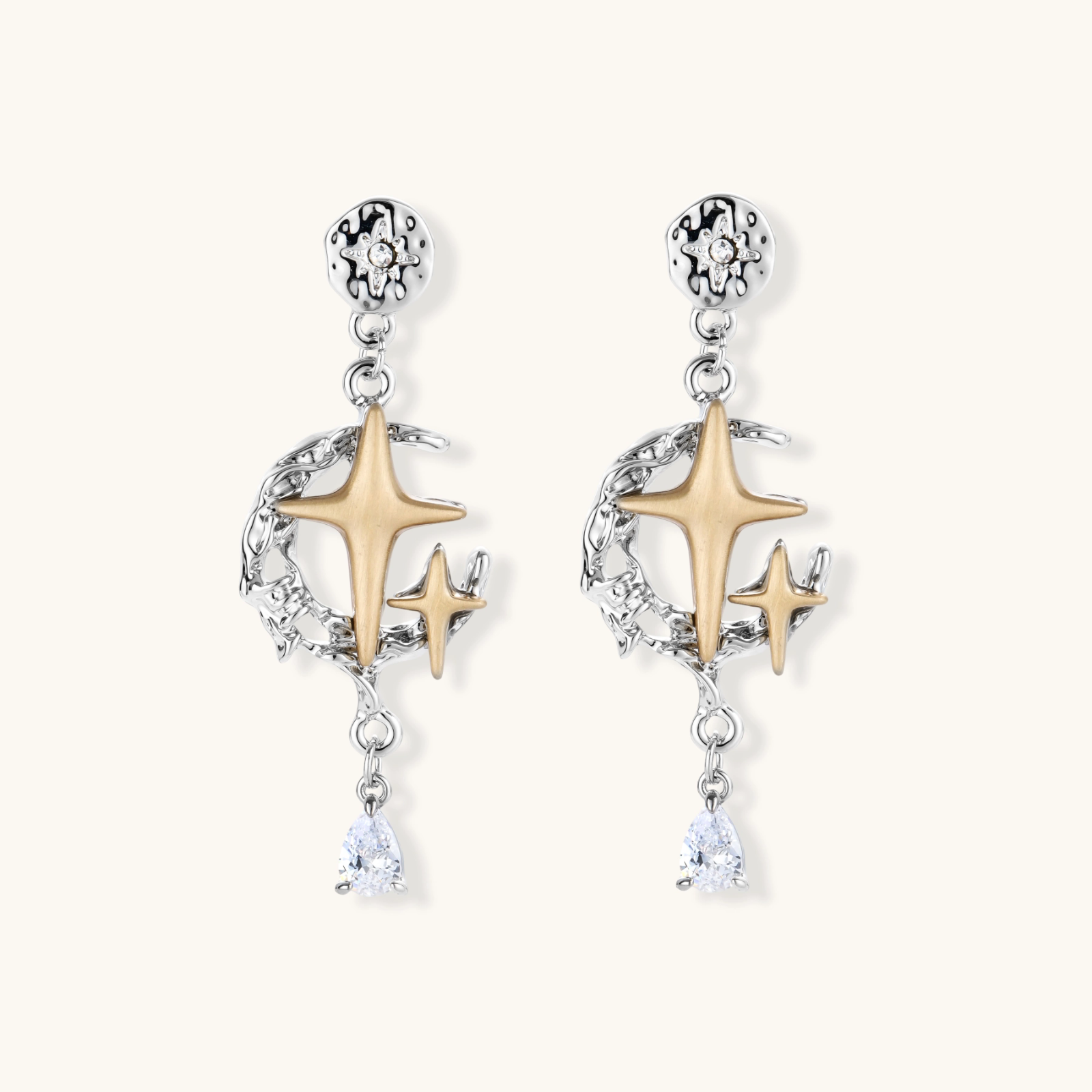 Two-tone star earrings with gold celestial motifs, silver chains, and clear crystal droplets on white background.