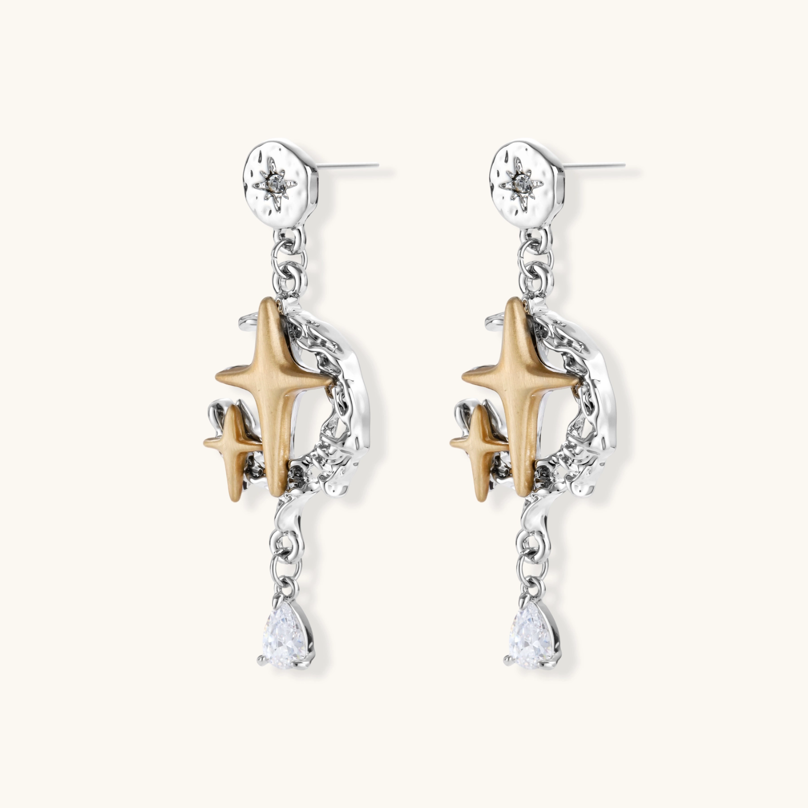 Two-tone star earrings with gold celestial motifs, silver chains, and clear crystal droplets on white background.