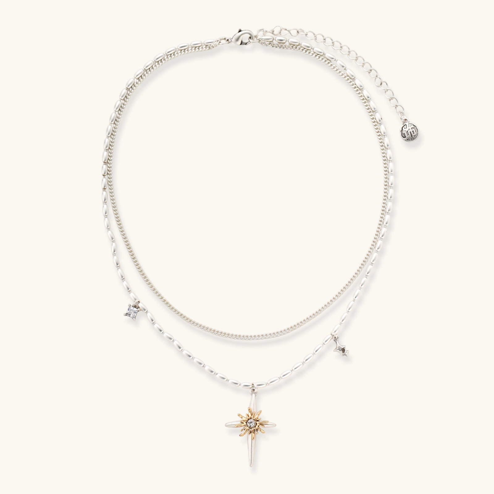 Two-layer silver-toned necklace with star charms and dagger pendant featuring golden sun motif on white background.