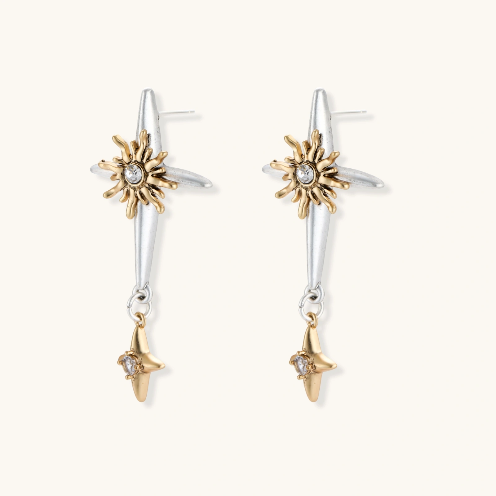 Dangle earrings with silver hoops, gold sun charms with crystals, and gold four-pointed star drops on cream background.