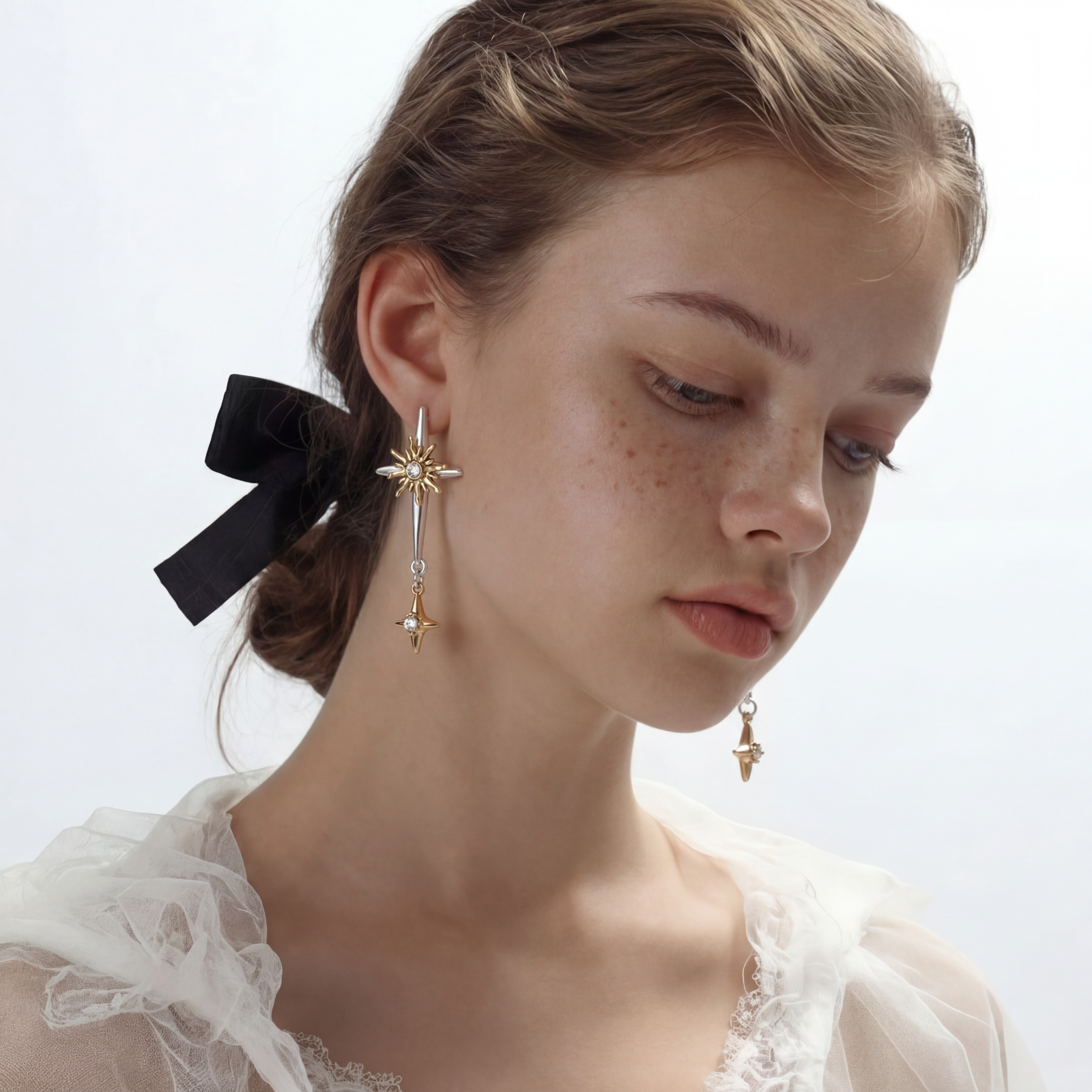 Dangle earrings with silver hoops, gold sun charms with crystals, and gold four-pointed star drops on cream background.