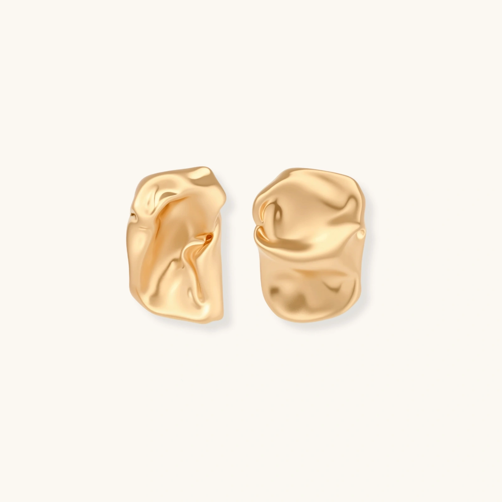 Abstract crumpled metallic earrings with fluid organic shapes in reflective gold and silver finish on neutral background.