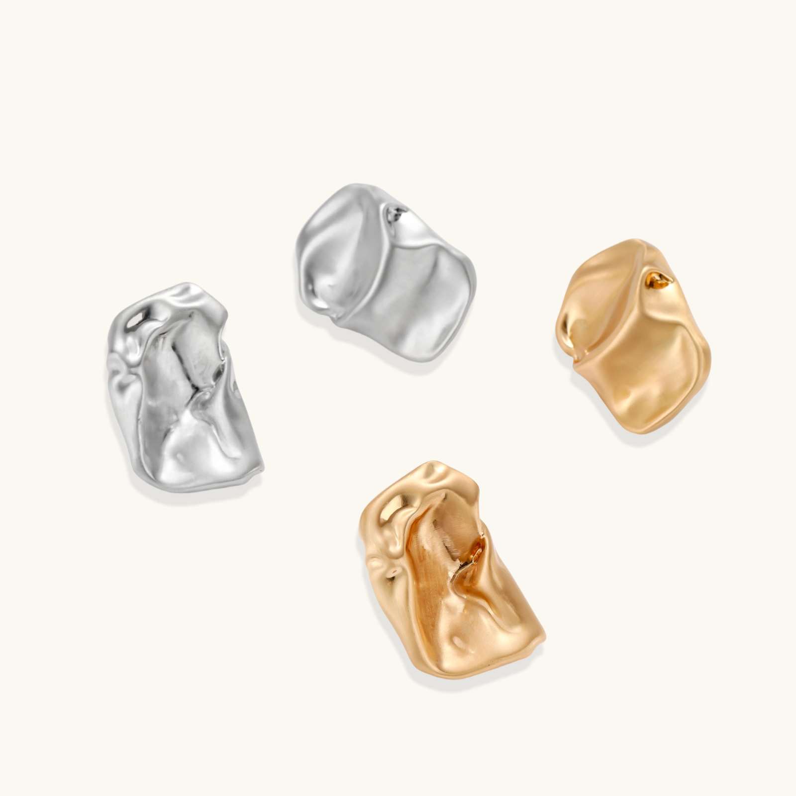 Abstract crumpled metallic earrings with fluid organic shapes in reflective gold and silver finish on neutral background.
