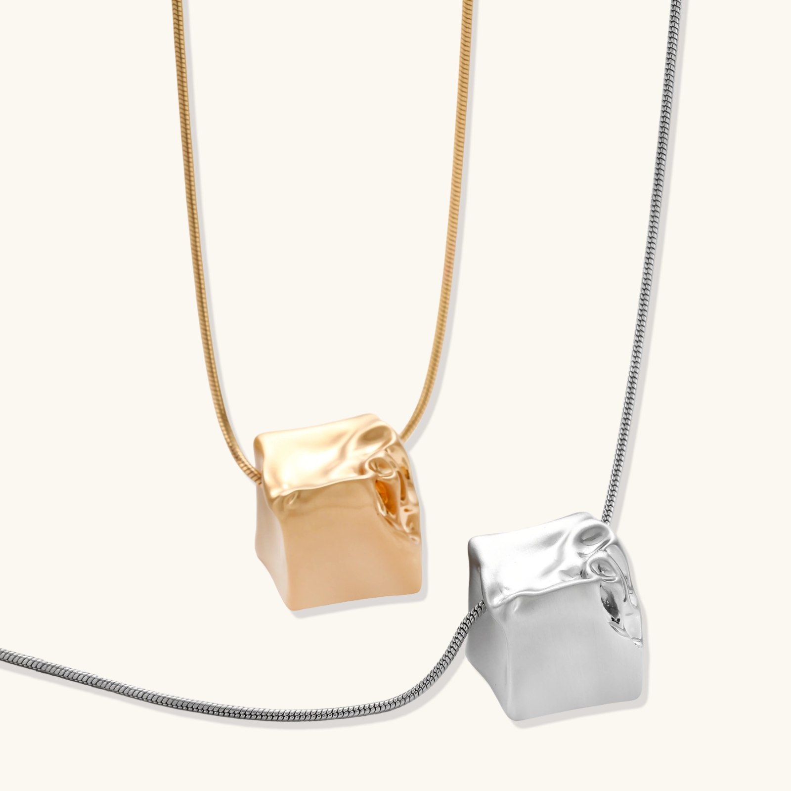 Modern cube pendant with liquid metal draping detail on adjustable chain, available in gold and silver finishes