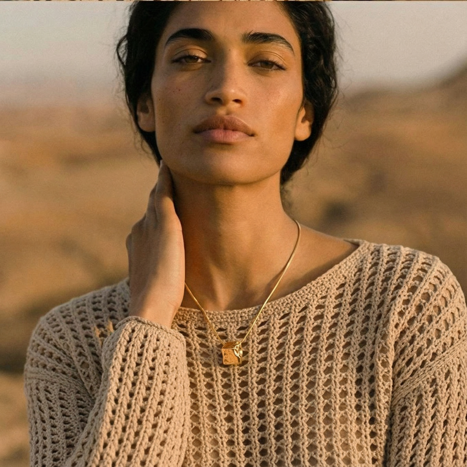 Modern cube pendant with liquid metal draping detail on adjustable chain, available in gold and silver finishes