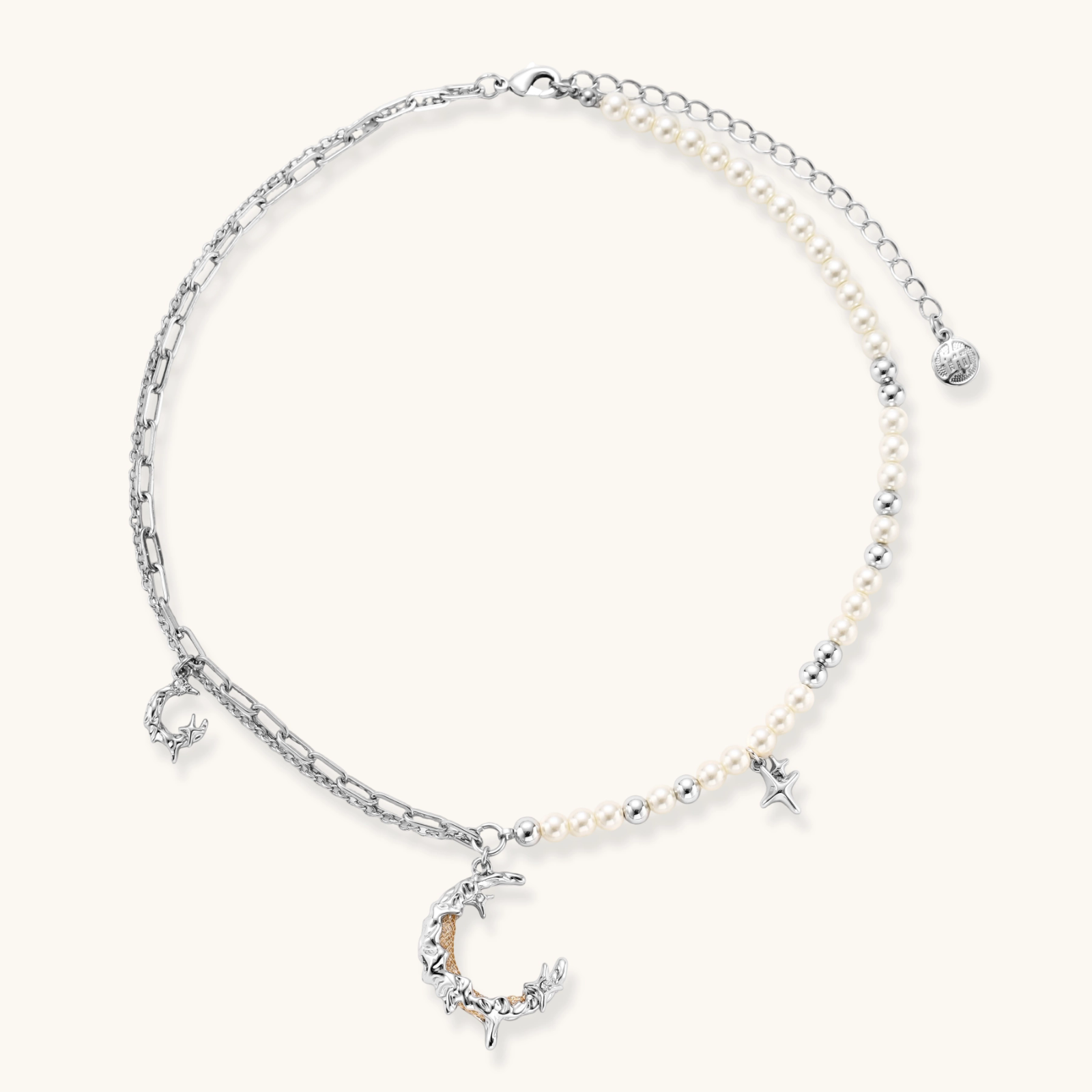 Silver-toned crescent moon pendant with star accents on pearl and chain necklace against white background.