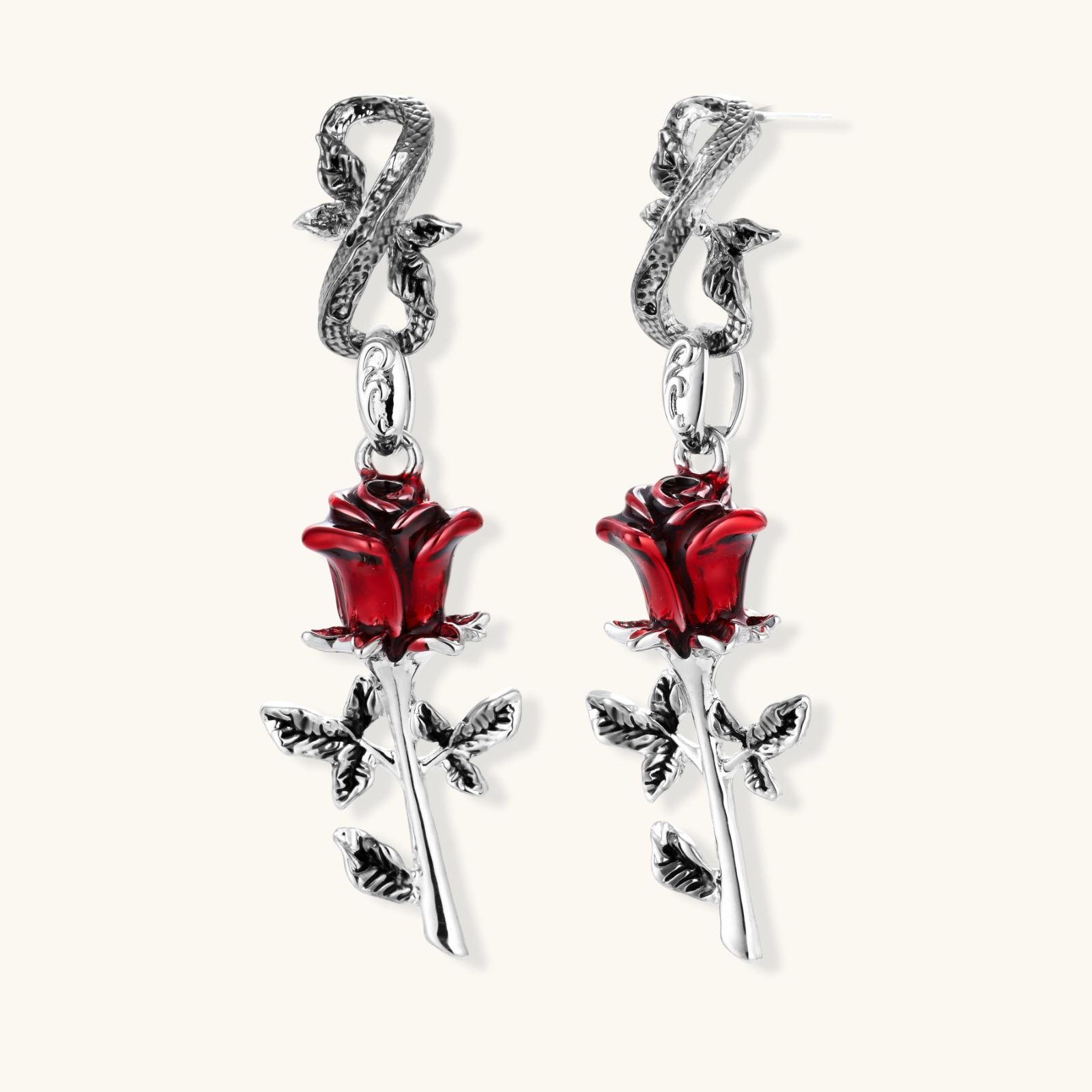 Gothic dangle earrings featuring silver serpent hooks with red enamel roses and metallic stems on white background.