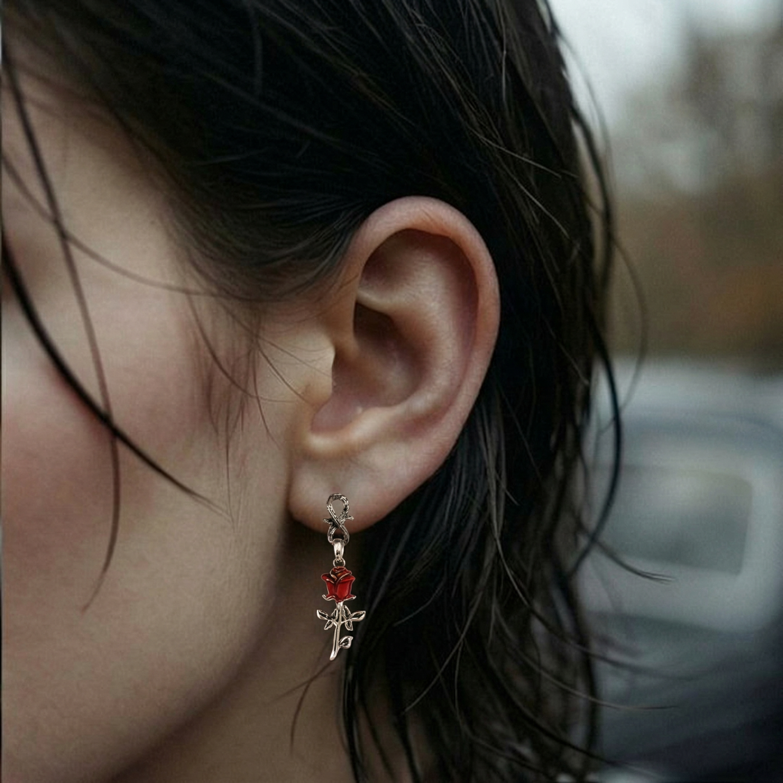 Gothic dangle earrings featuring silver serpent hooks with red enamel roses and metallic stems on white background.