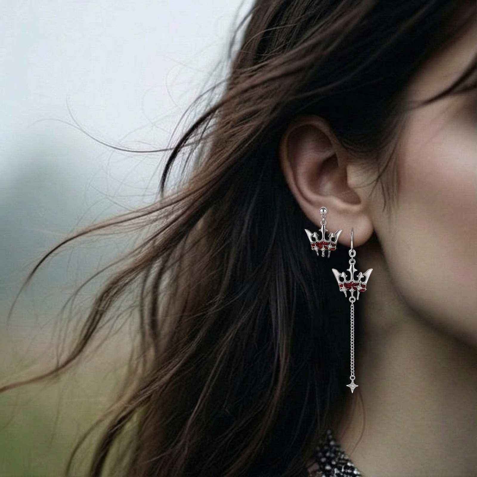 Asymmetrical crown-shaped stud earrings with red zirconia stones, one featuring a silver chain with star charm