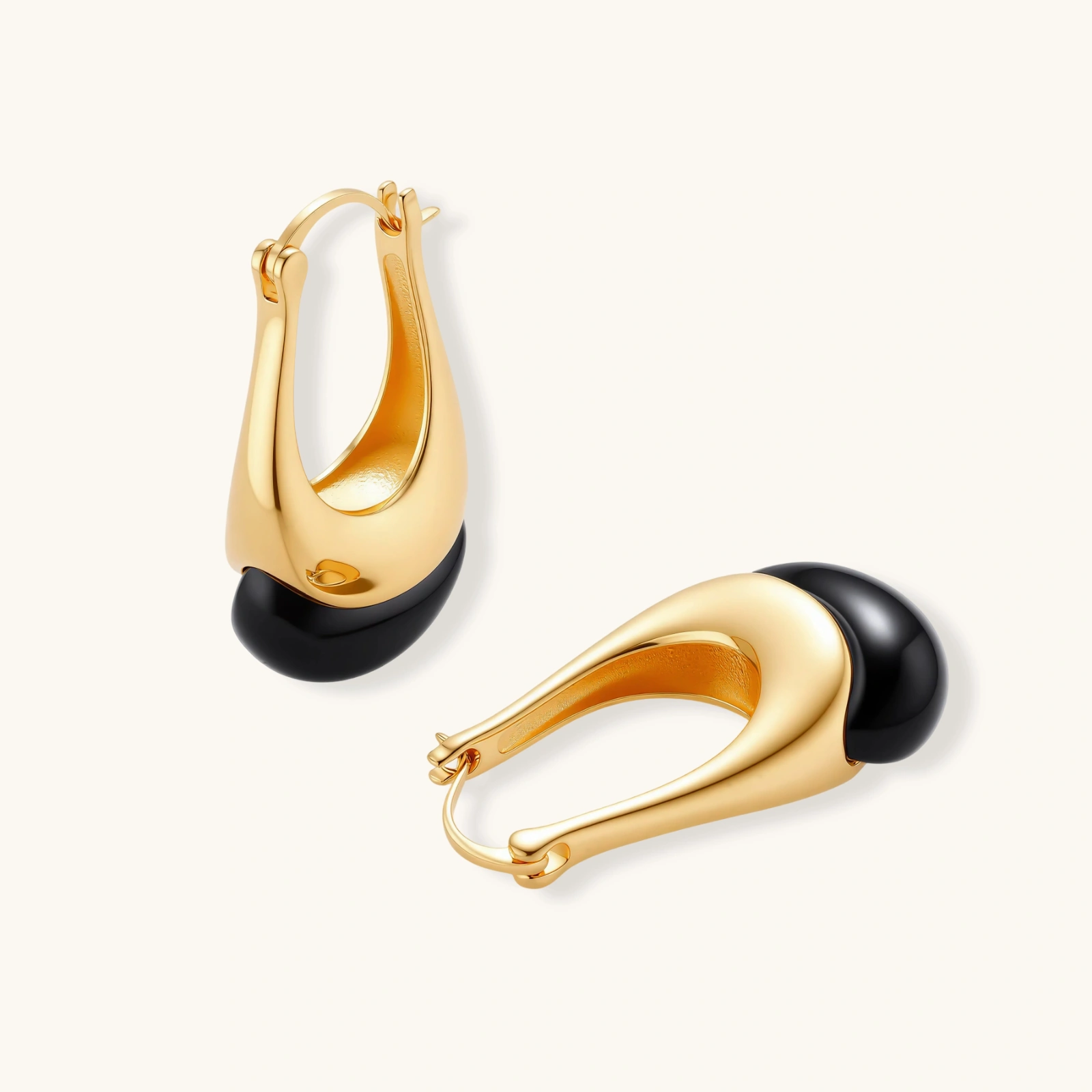 Gold-plated drop earrings featuring black agate stones with hoop closure on white background, showing elegant teardrop design.