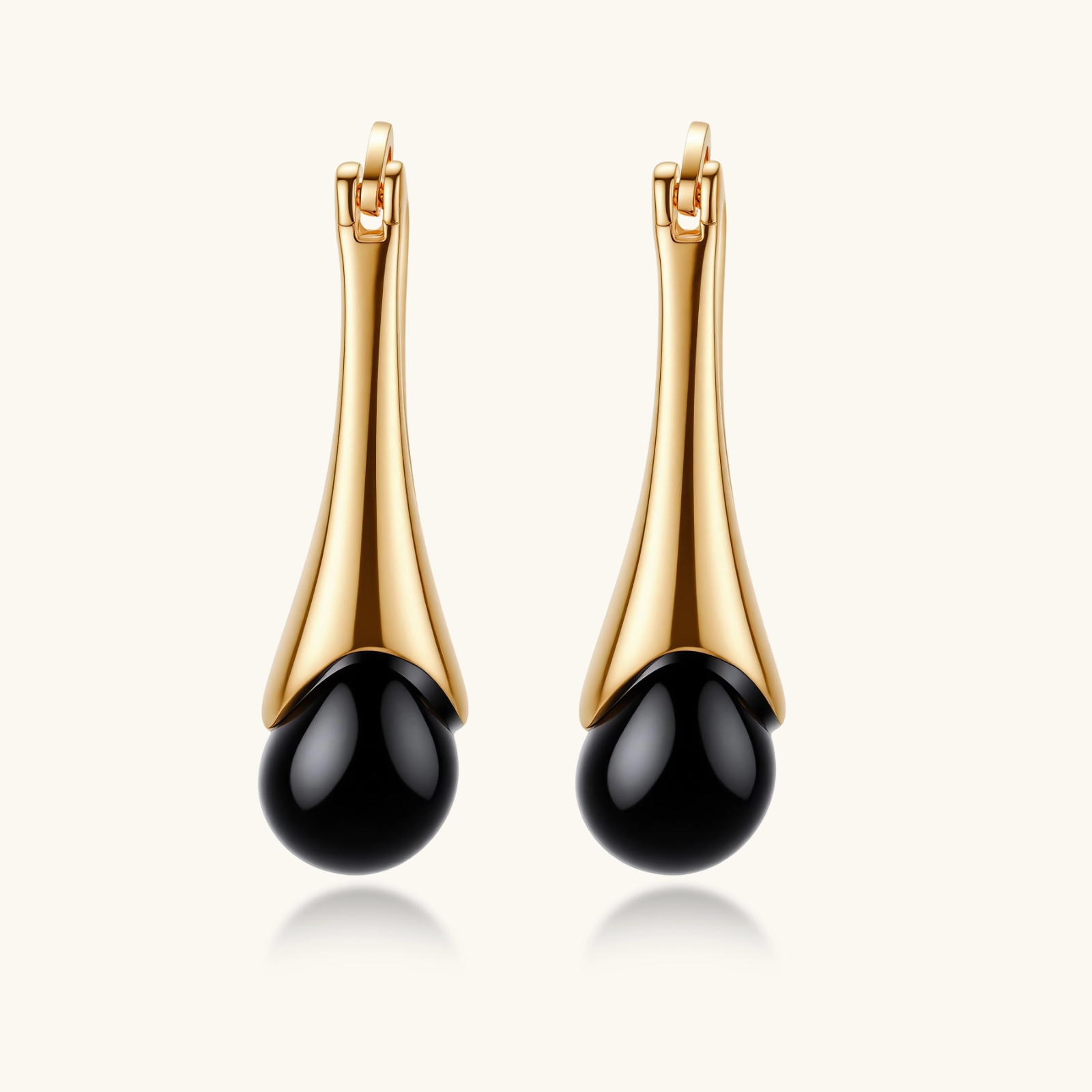 Gold-plated drop earrings featuring black agate stones with hoop closure on white background, showing elegant teardrop design.