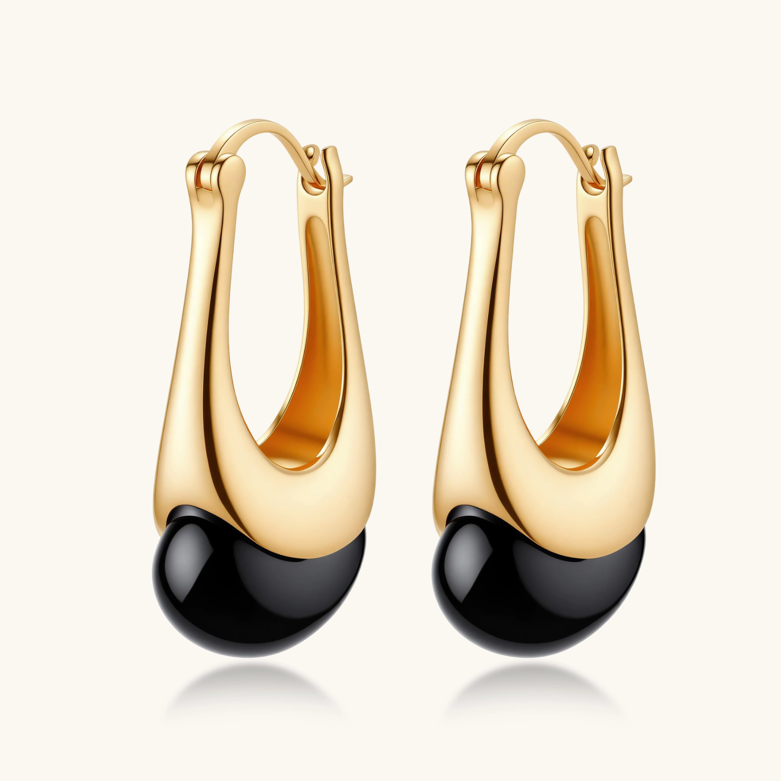 Gold-plated drop earrings featuring black agate stones with hoop closure on white background, showing elegant teardrop design.