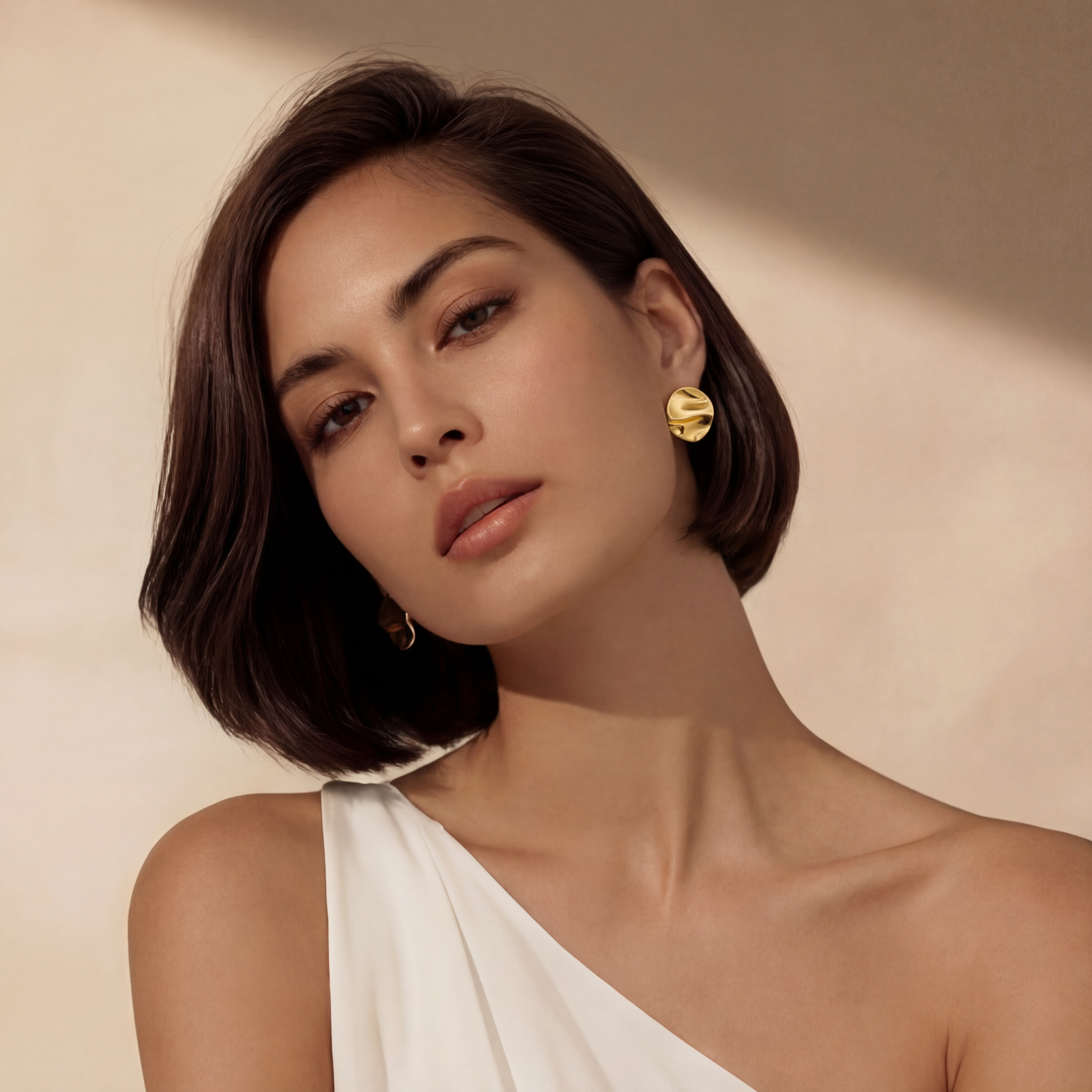 Close-up of organic gold-plated sterling silver stud earrings with flowing sculptural design and curved cut-outs