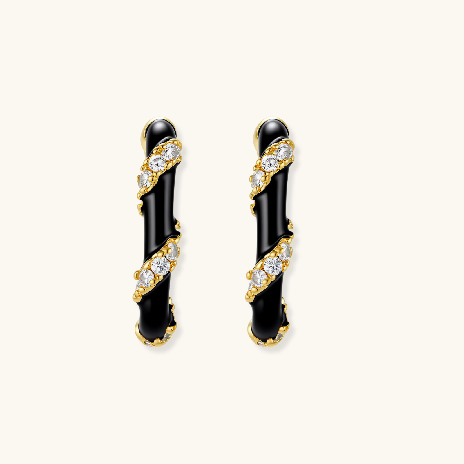Small gold-plated hoop earrings with black enamel stripes and cubic zirconia crystals on white background.