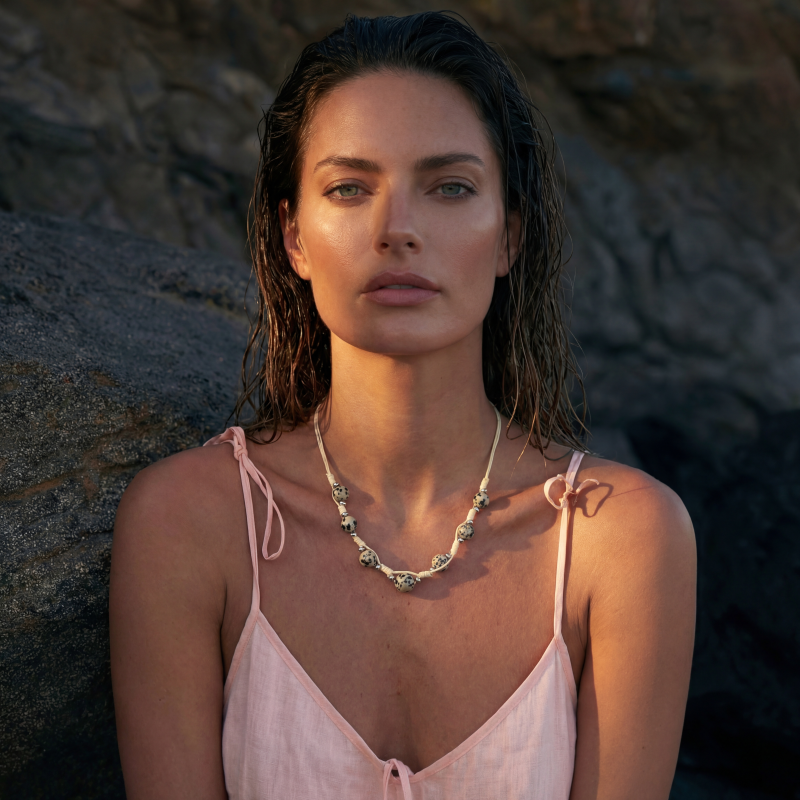 Adjustable cream cord necklace with white spotted stone beads featuring black speckles on neutral background
