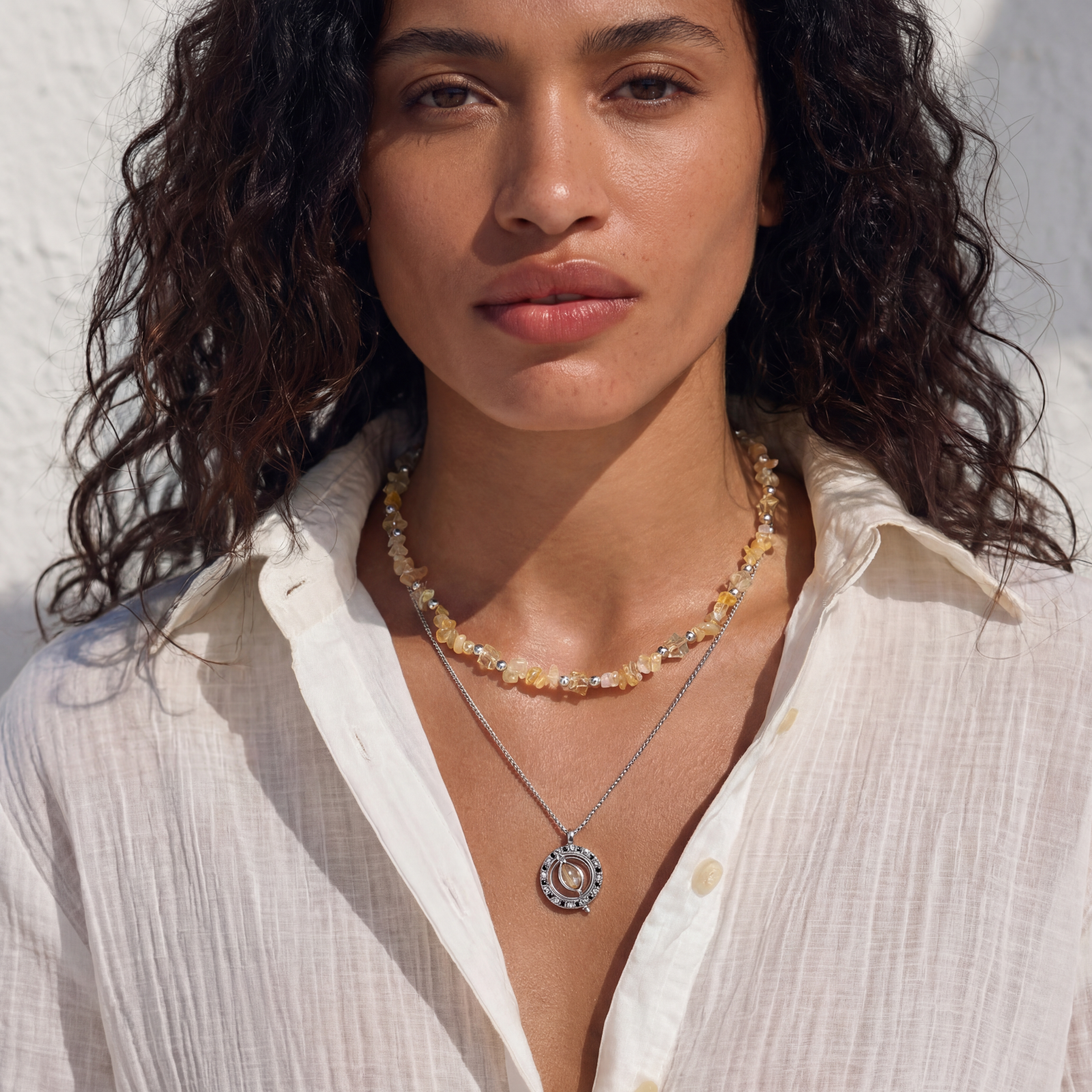 Two-layer necklace with natural stone chips and eco-brass beads, featuring a circular wrapped pendant on cream background.