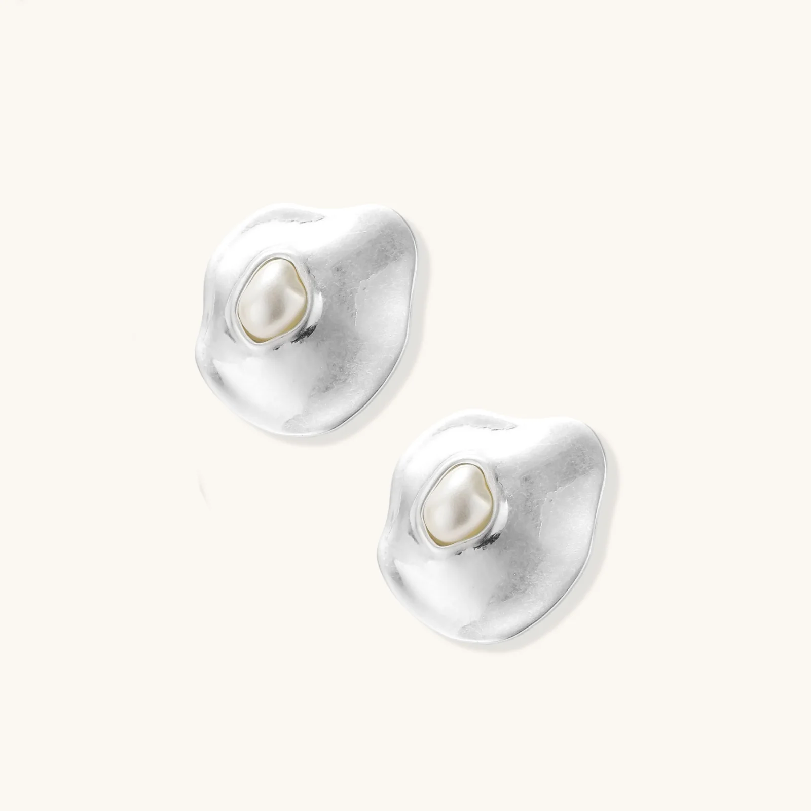 Organic-shaped eco-zinc alloy stud earrings with resin pearl centers and sterling silver posts on white background.