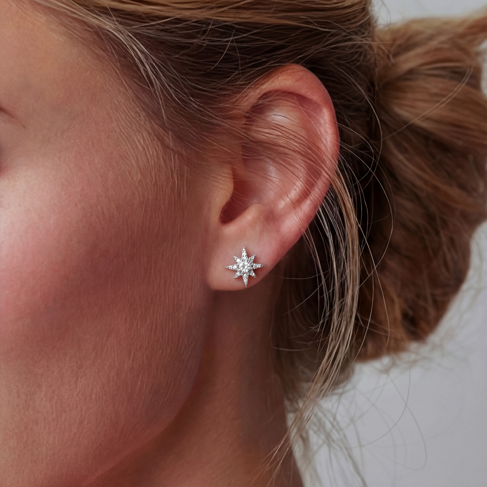 Sterling silver star-shaped stud earrings with brilliant moissanite center stones and pavé details on neutral background.
