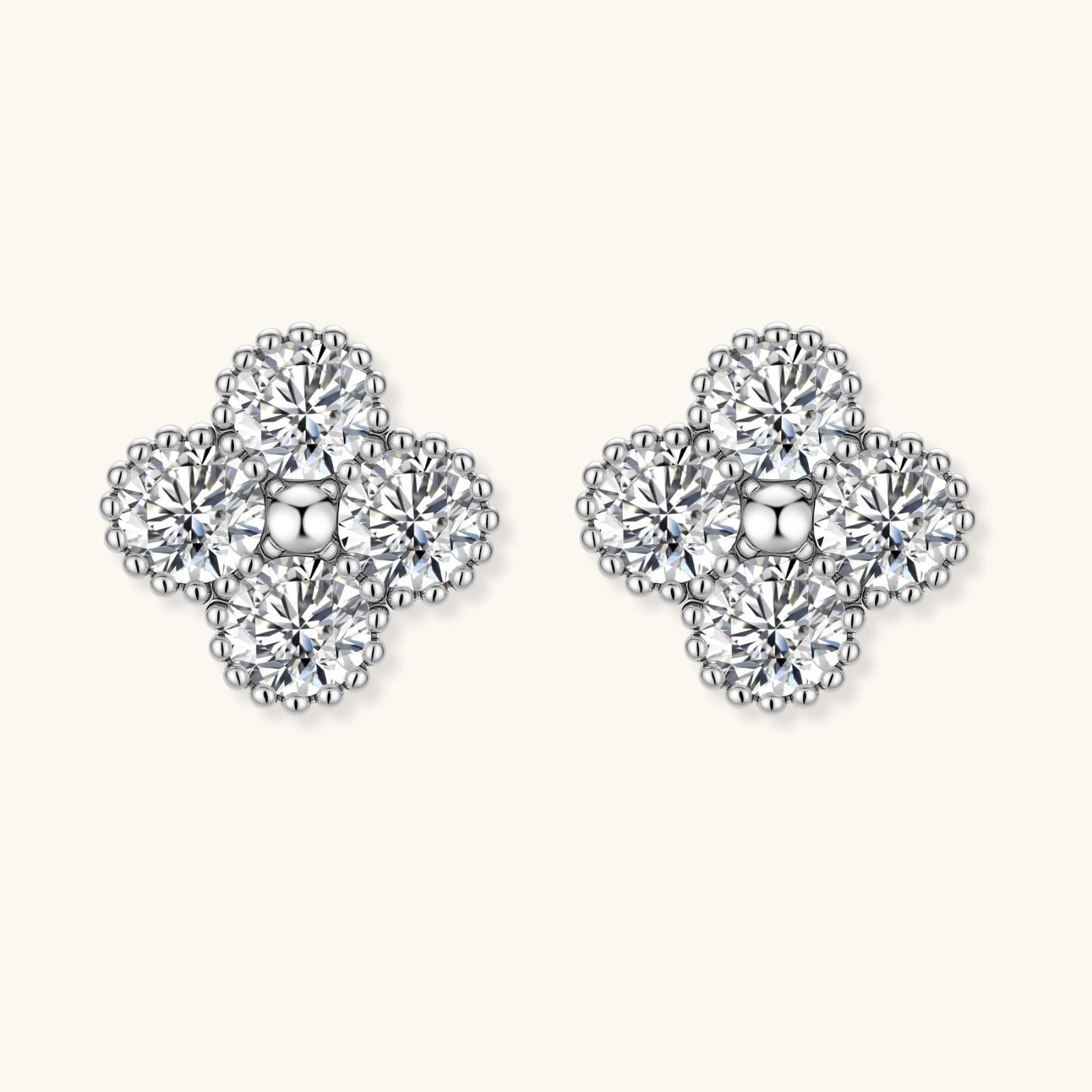Dainty sterling silver quatrefoil stud earrings with four brilliant moissanite stones and center accent on white background.