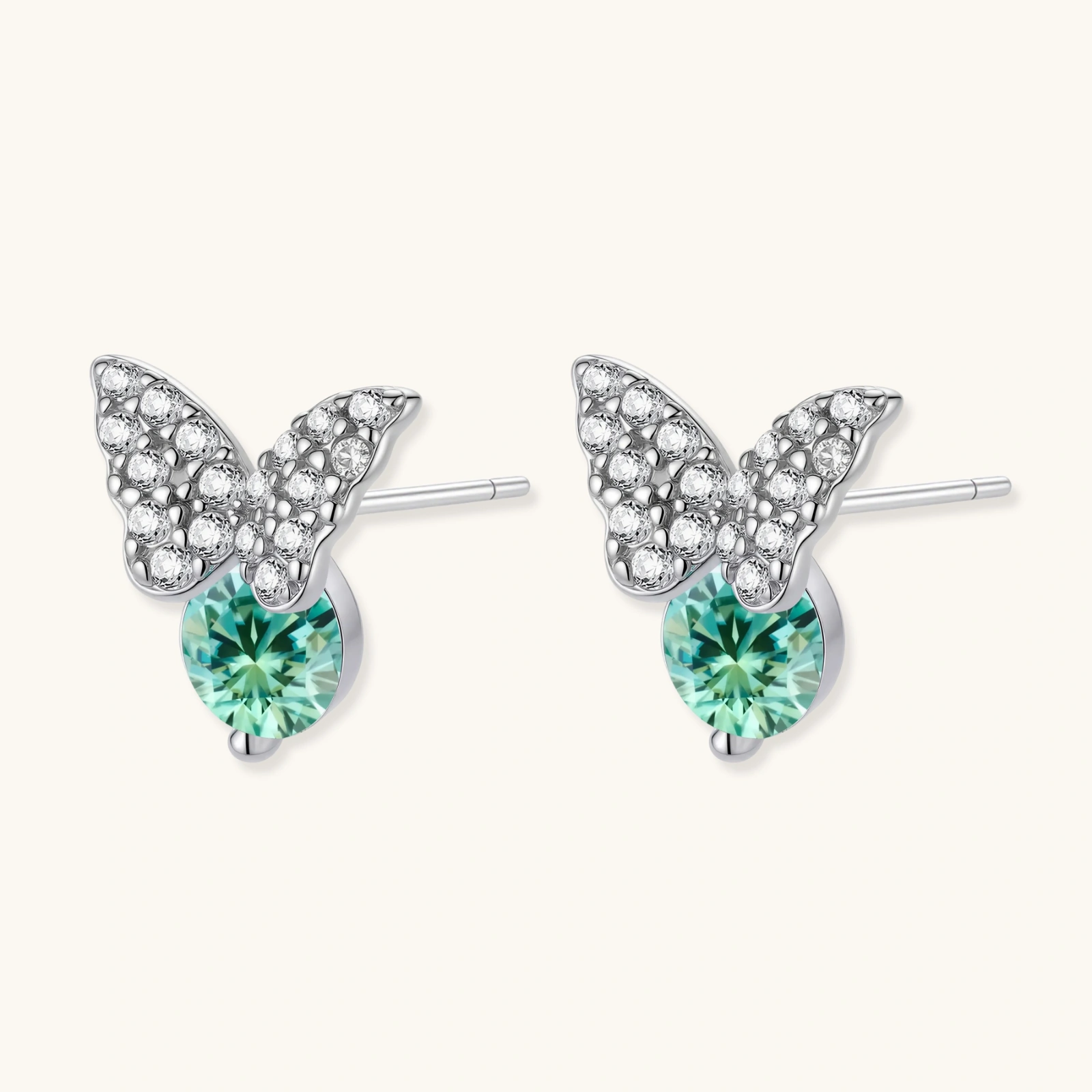 Sterling silver butterfly stud earrings with crystal wings and mint green center stones on cream background.
